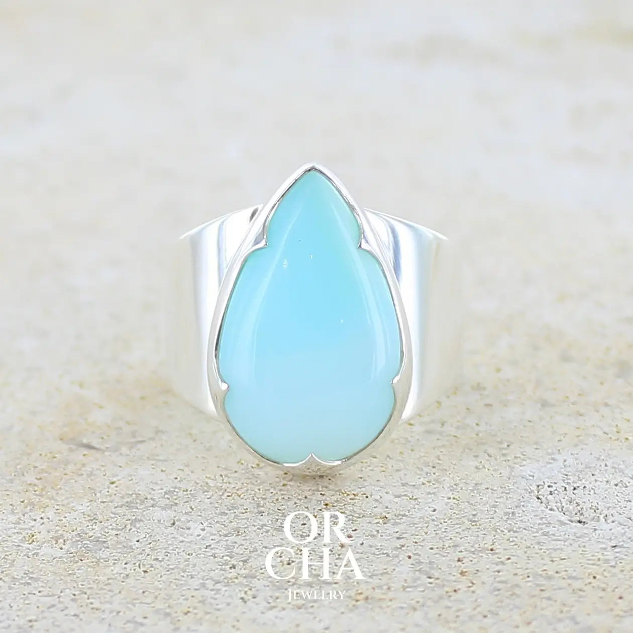 Bague pour femme en argent massif, sertie d'un cabochon d'opale bleue du Pérou de couleur bleu ciel. Pierre taillée en forme de goutte de qualité opaque. Bijou unique réalisé en taille 58. 