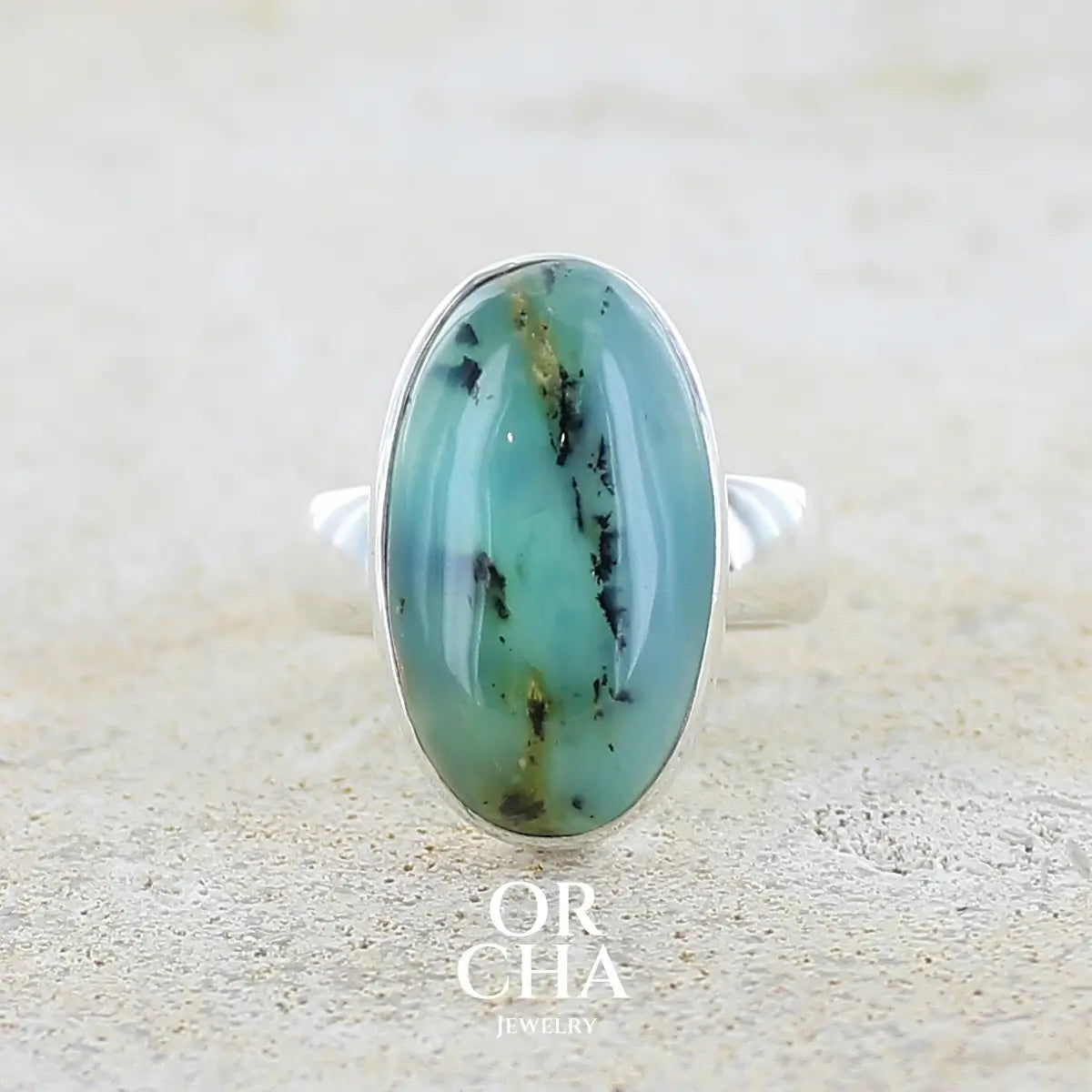 Bague en argent massif, sertie d'un cabochon ovale d'opale bleue du Pérou de couleur bleu foncé à inclusions de dendrites paysages noires et de roche mère jaune. Pierre naturelle opaque et translucide. Bijoux unique réalisé en taille 52 par Orcha jewelry