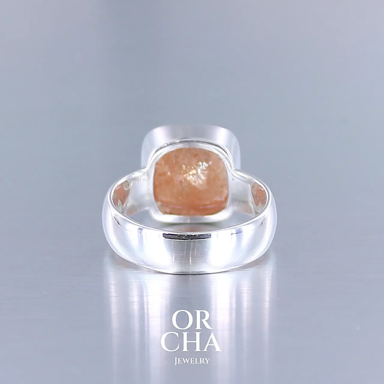 vue arrière d'une bague cocktail pour femme en argent massif sertie d'une pierre de soleil oranges de très belle qualité, pierre transparente avec inclusions scintillantes d'hématites. Pierre naturelle facettée de forme carrée. Tailles 56. Bijoux unique, éthique et durable présenté dans un coffret de notre marque, prêt à offrir. Livraison offerte, certificat d'authenticité, service client.