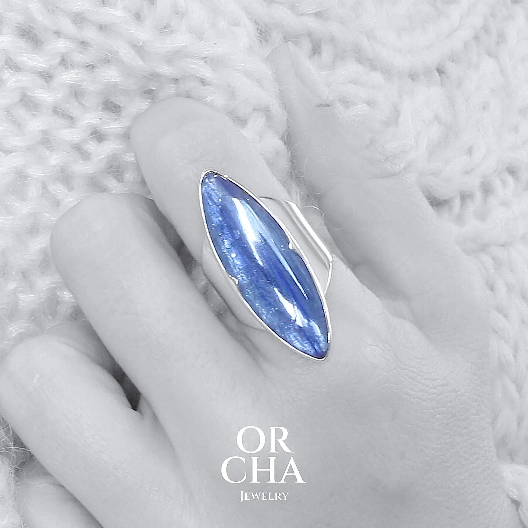 Grande bague pour femme en argent massif sertie d'une Cyanite. Pierre cabochon en forme navette, pierre naturelle de couleur bleue nacrée. Pierre fine de qualité translucide présentant des inclusions. Taille 60. Bijoux unique, éthique et durable présenté dans un coffret de notre marque, prêt à offrir. Livraison offerte, certificat d'authenticité, service client