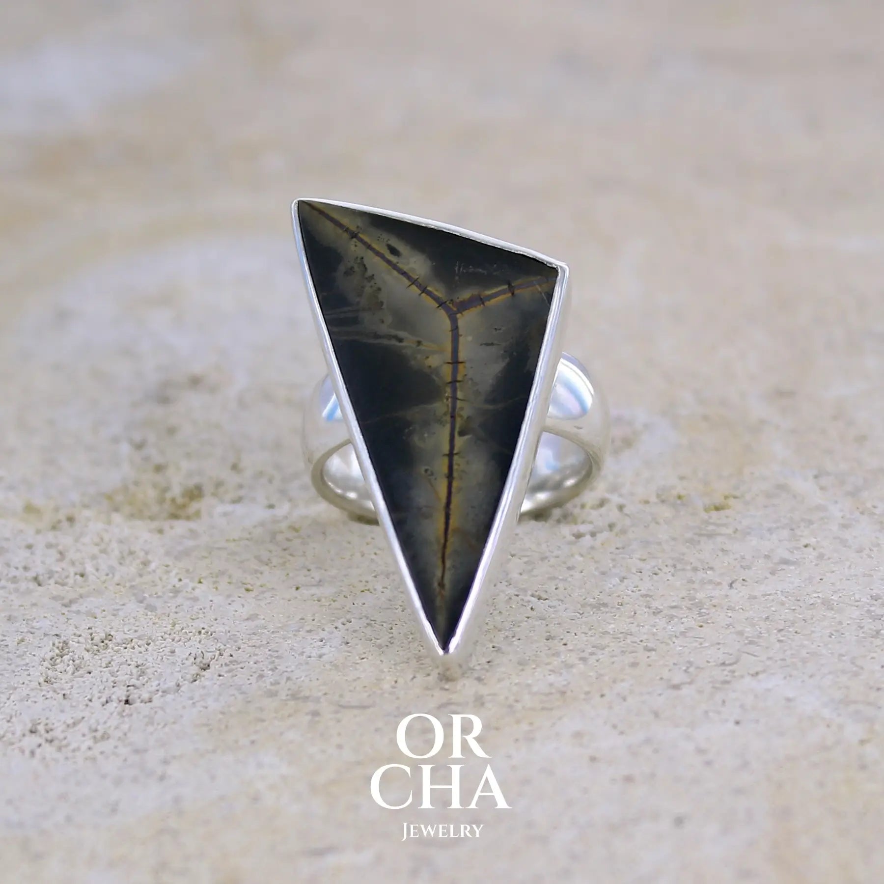 Grande bague contemporaine pour femme en argent massif sertie d'une tranche de septaria Pierre unique et rare sous cette forme triangulaire. Pierre de qualité opaque naturelle de couleur brun foncé à brun clair. Bague réalisée en taille 54.  Bijoux unique, éthique et durable présenté dans un coffret de notre marque, prêt à offrir. Livraison offerte, certificat d'authenticité, service client.
