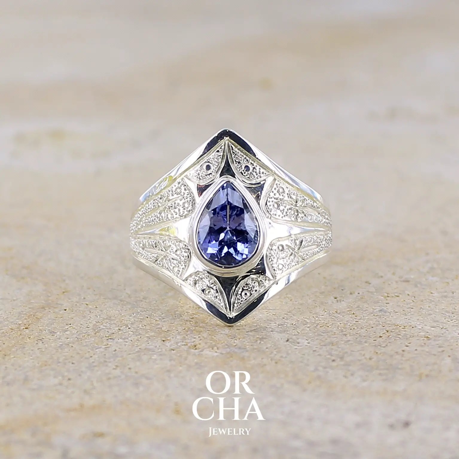 Bague pour femme en argent massif sculptée d'étoiles et autres corps célestes sertie d'une Tanzanite de couleur bleu lavande. Pierre naturelle, facettée en forme de forme goutte, de qualité transparente présentant un très bel éclat. Taille 58. Bijoux unique, éthique et durable présenté dans un coffret de notre marque, prêt à offrir. Livraison offerte, certificat d'authenticité, service client.

