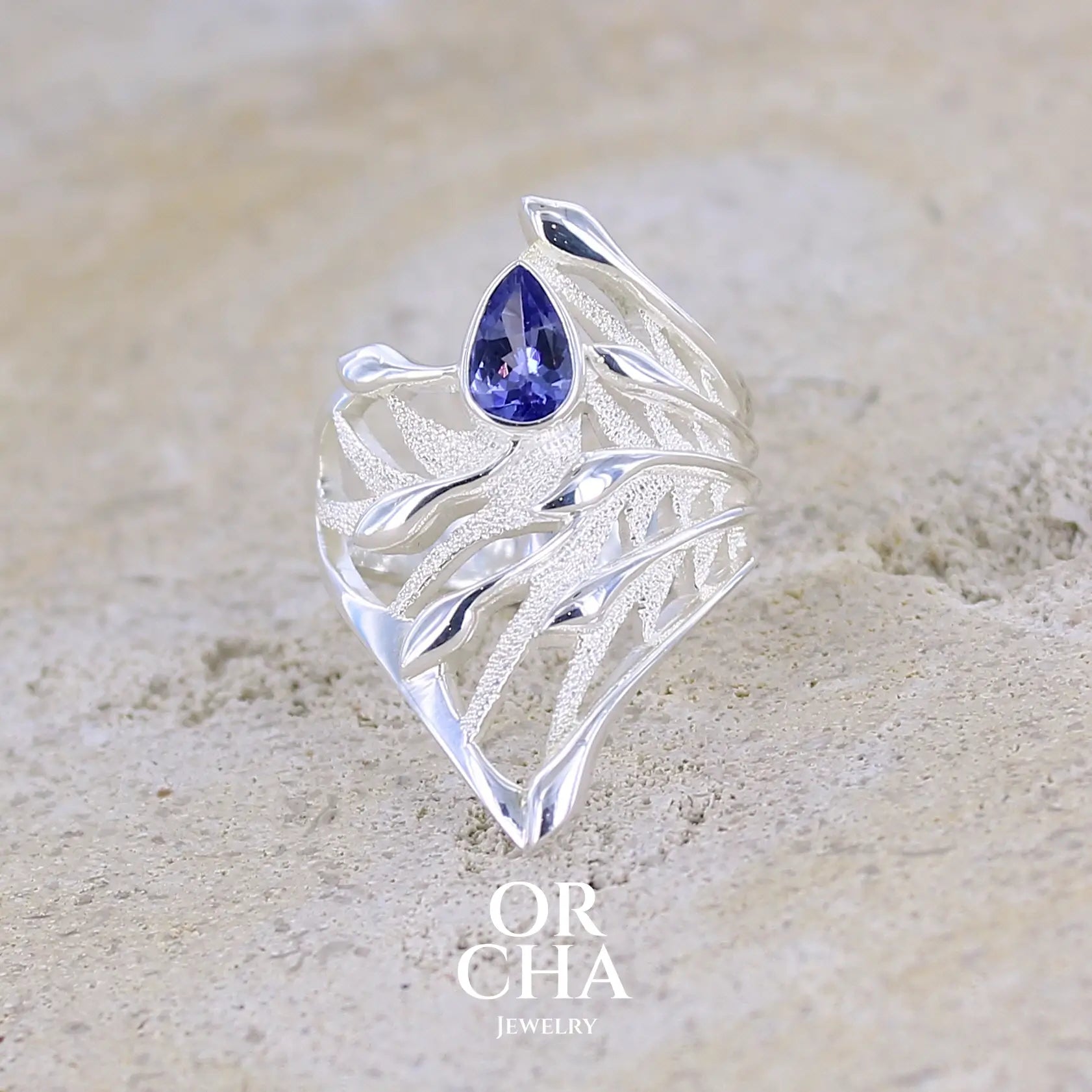 Grande Bague pour femme, feuillage tropicale travaillé en filigrane en argent massif, sertie d'une Tanzanite bleu lavande. Pierre facettée en forme de goutte. Pierre lumineuse et propre à l'oeil. Bijoux unique, éthique et durable présenté dans un coffret de notre marque, prêt à offrir. Livraison offerte, certificat d'authenticité, service client.
