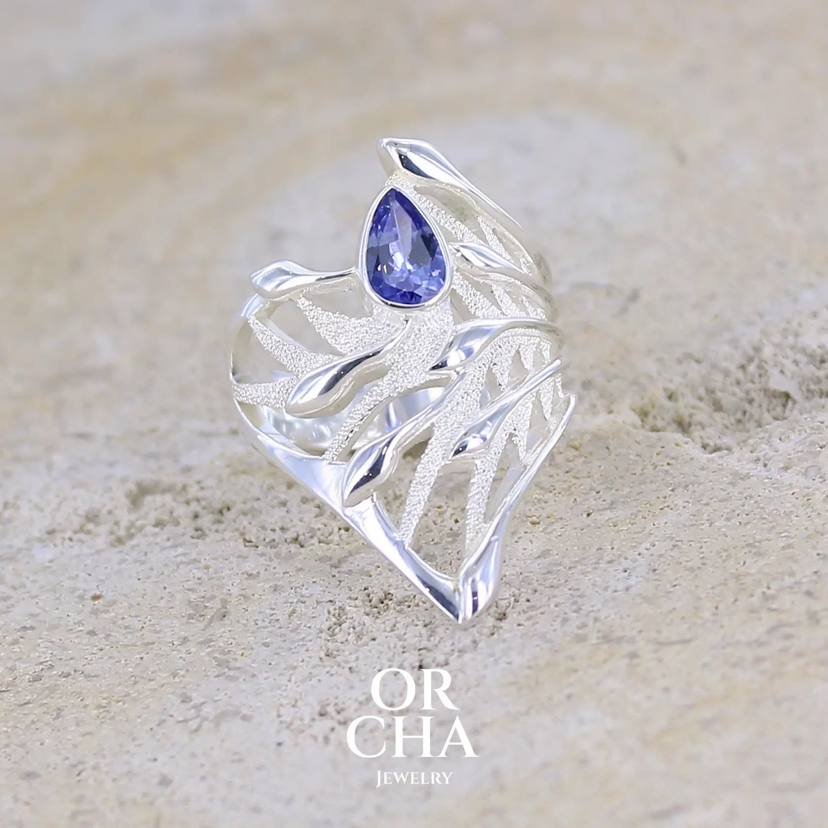 Grande Bague pour femme, feuillage tropicale travaillé en filigrane en argent massif, sertie d'une Tanzanite bleu lavande. Pierre facettée en forme de goutte. Pierre lumineuse et propre à l'oeil. Bijoux unique, éthique et durable présenté dans un coffret de notre marque, prêt à offrir. Livraison offerte, certificat d'authenticité, service client.