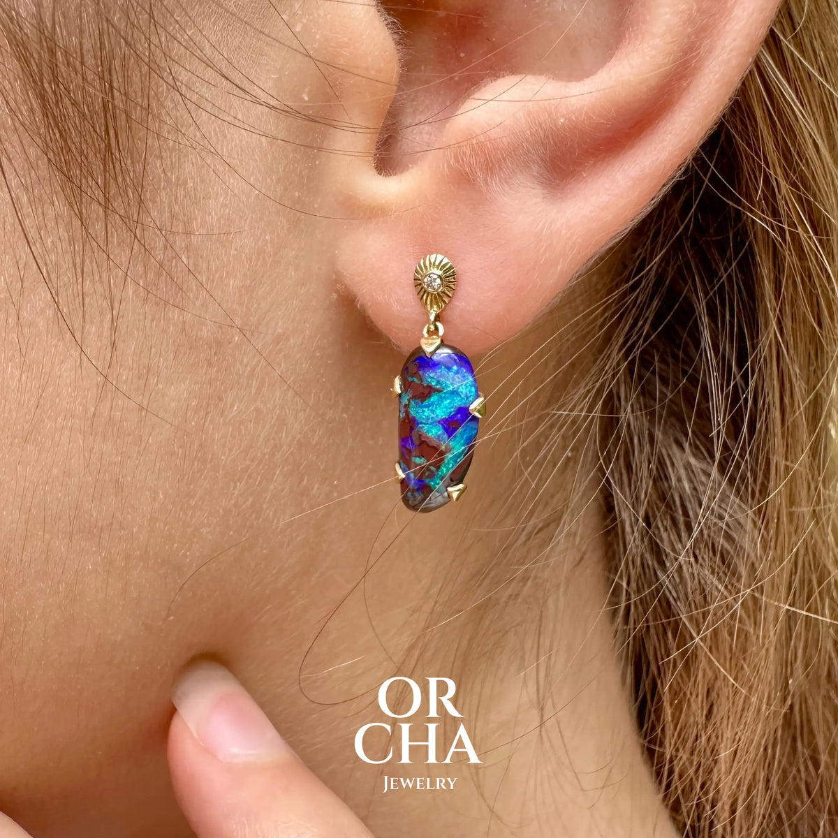 Boucles d'oreilles pendantes en or 18k serties d'opales aux feux multicolores turquoises et bleus violets, ainsi que de diamants. Pierres cabochons de qualité opaque. Bijoux uniques par Orchajewelry.