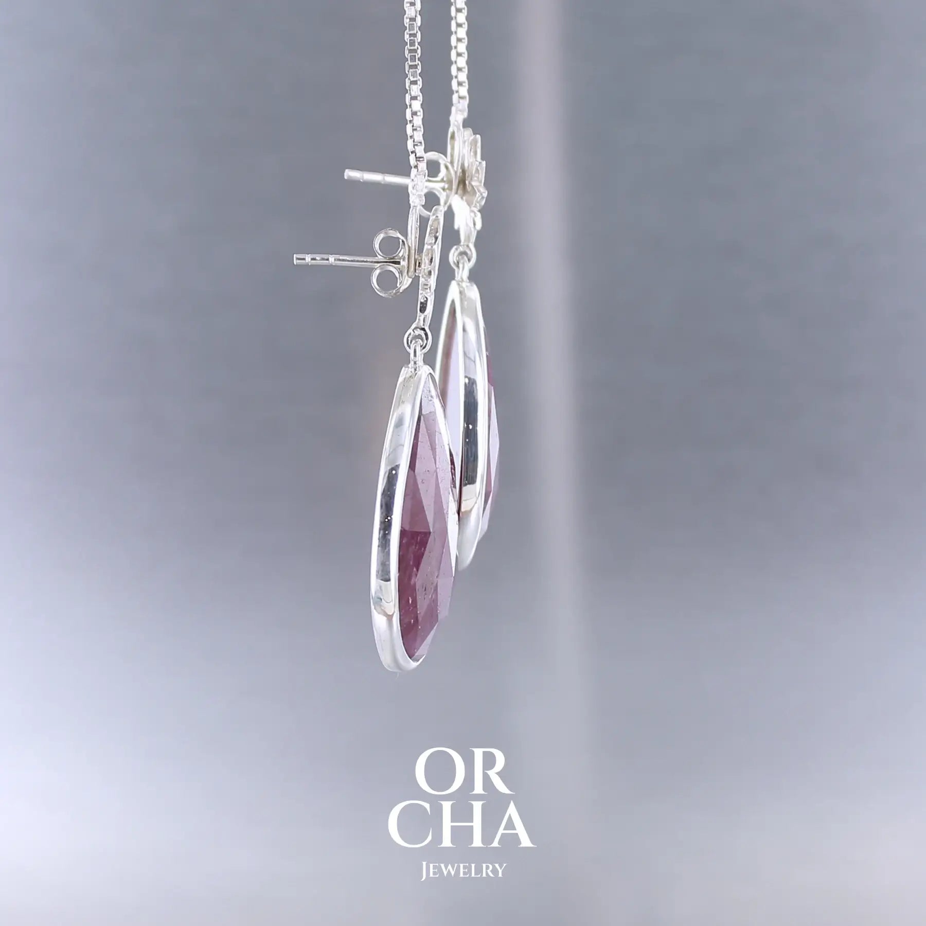 Boucles d'oreilles lotus pour femme en argent massif sertie de rubis. Cabochons facettés en forme de goutte de qualité opaque. Pierre naturelle de couleur rouge violacé. Le clou des boucles représente un lotus. Bijoux unique, éthique et durable présenté dans un coffret de notre marque, prêt à offrir. Livraison offerte, certificat d'authenticité, service client.