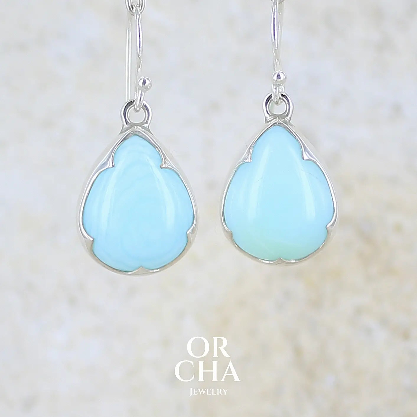 Boucles d'oreilles pendantes en argent massif serties d'opale bleue du Pérou. Pierres cabochon taillée en goutte de qualité opaque. Pierre naturelle de couleur bleu ciel. Bijoux unique, éthique et durable présenté dans un coffret de notre marque, prêt à offrir. Livraison offerte, certificat d'authenticité, service client.
