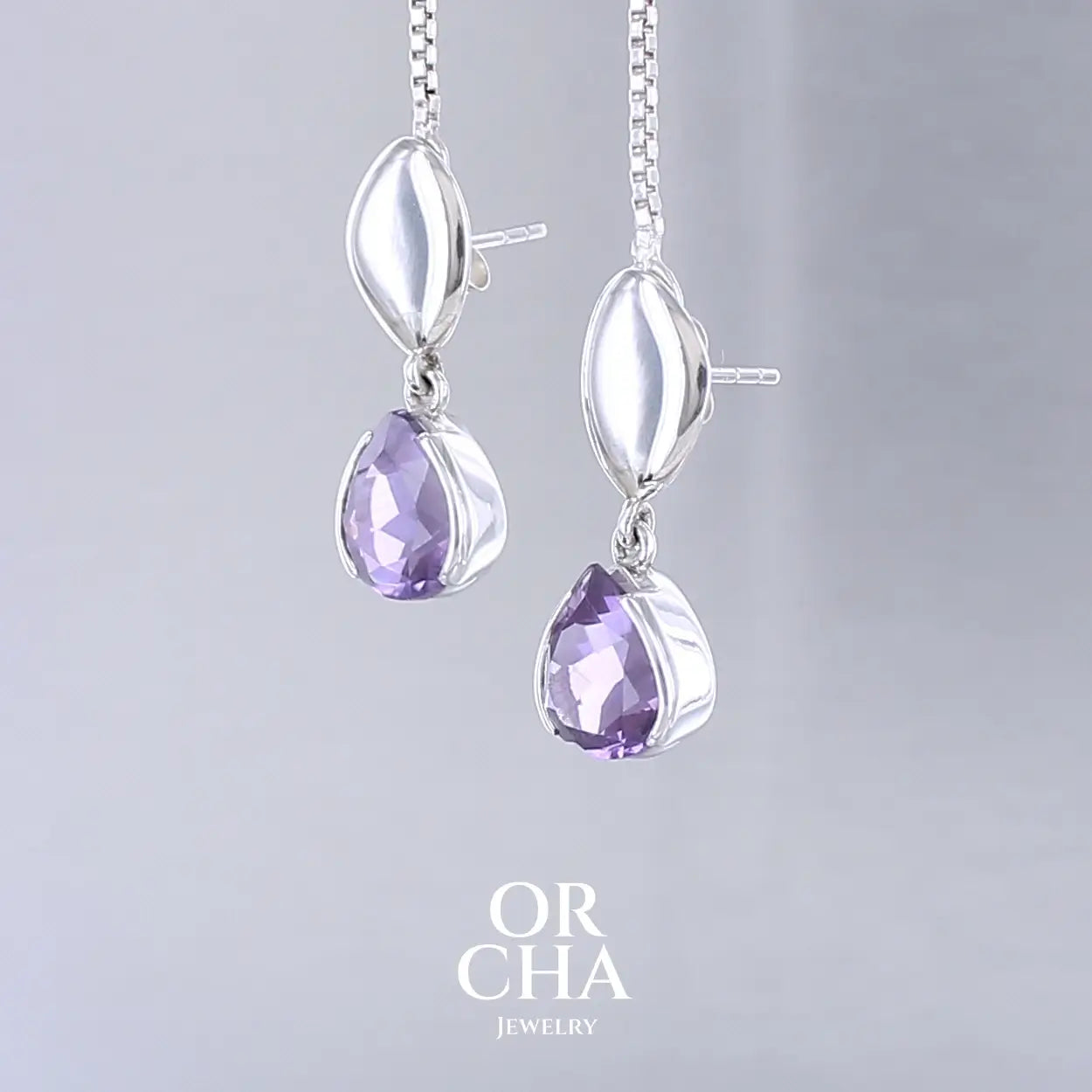 Boucles d'oreilles pendantes pour femme en argent massif serties d'Améthyste. Pierres facettées en forme de goutte de qualités transparentes, propre à l'oeil. Pierres naturelles de couleur violet moyen .Bijoux unique, éthique et durable présenté dans un coffret de notre marque, prêt à offrir. Livraison offerte, certificat d'authenticité, service client.