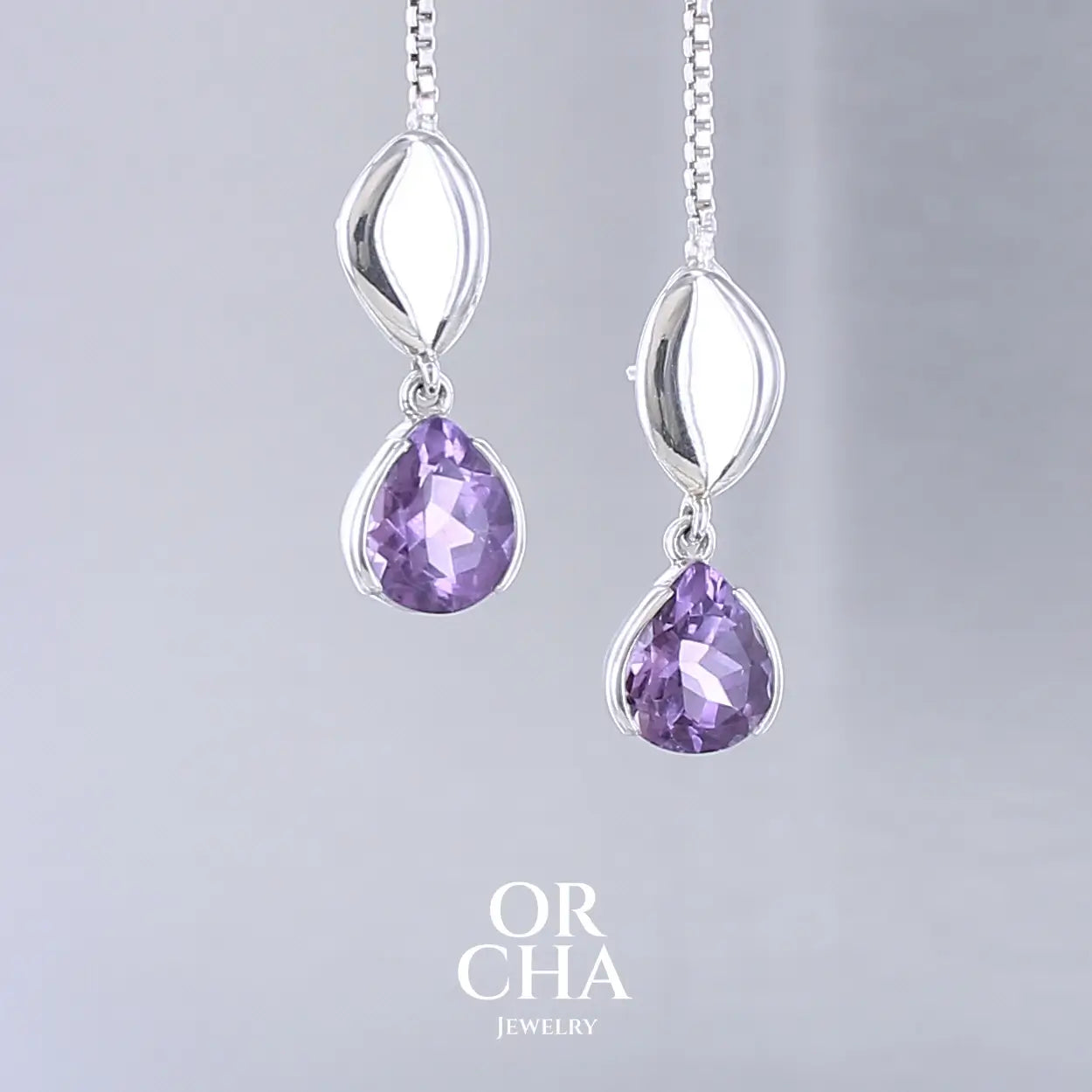 Boucles d'oreilles pendantes pour femme en argent massif serties d'Améthyste. Pierres facettées en forme de goutte de qualités transparentes, propre à l'oeil. Pierres naturelles de couleur violet moyen .Bijoux unique, éthique et durable présenté dans un coffret de notre marque, prêt à offrir. Livraison offerte, certificat d'authenticité, service client.