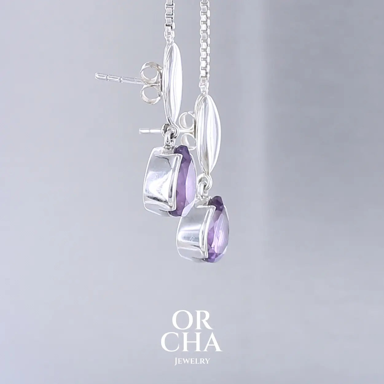 Boucles d'oreilles pendantes pour femme en argent massif serties d'Améthyste. Pierres facettées en forme de goutte de qualités transparentes, propre à l'oeil. Pierres naturelles de couleur violet moyen .Bijoux unique, éthique et durable présenté dans un coffret de notre marque, prêt à offrir. Livraison offerte, certificat d'authenticité, service client.