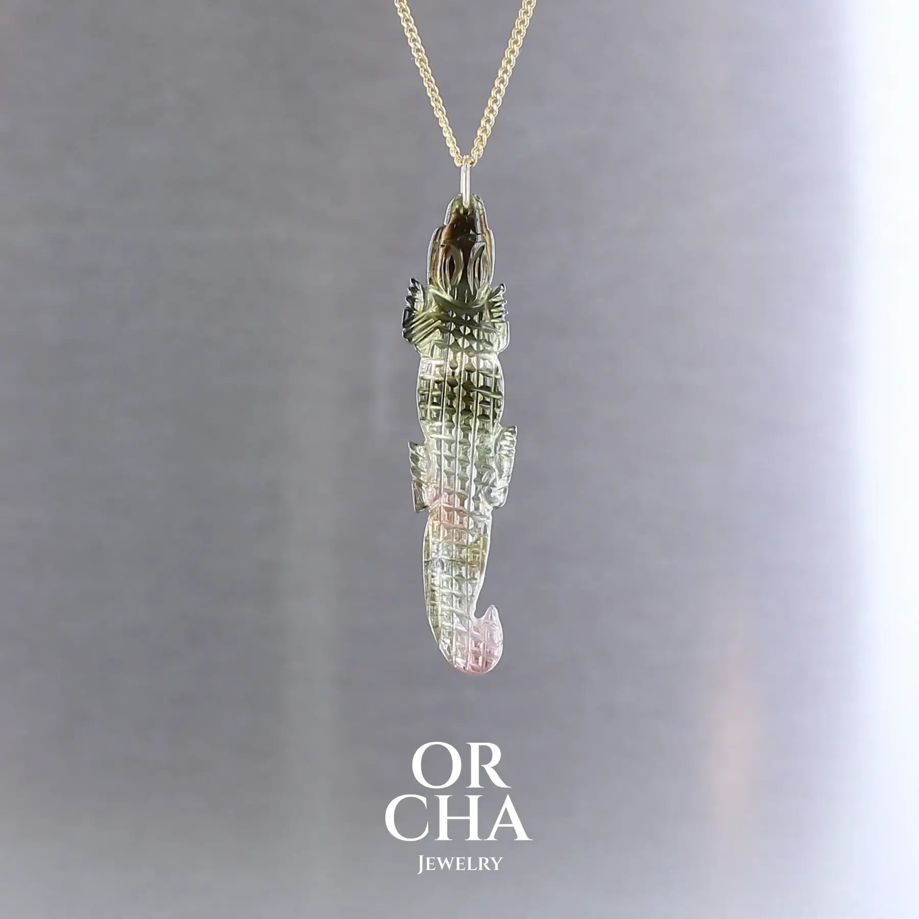 Collier pour homme orné d'une tourmaline melon d'eau sculptée à la main en 3 dimensions en forme de crocodile sertie en or 18k. Le pendentif est vendu sur une chaine de 45 cm de long en Gold filled ( or laminé ). Bijoux unique, éthique et durable présenté dans un coffret de notre marque, prêt à offrir. Livraison offerte, certificat d'authenticité, service client.