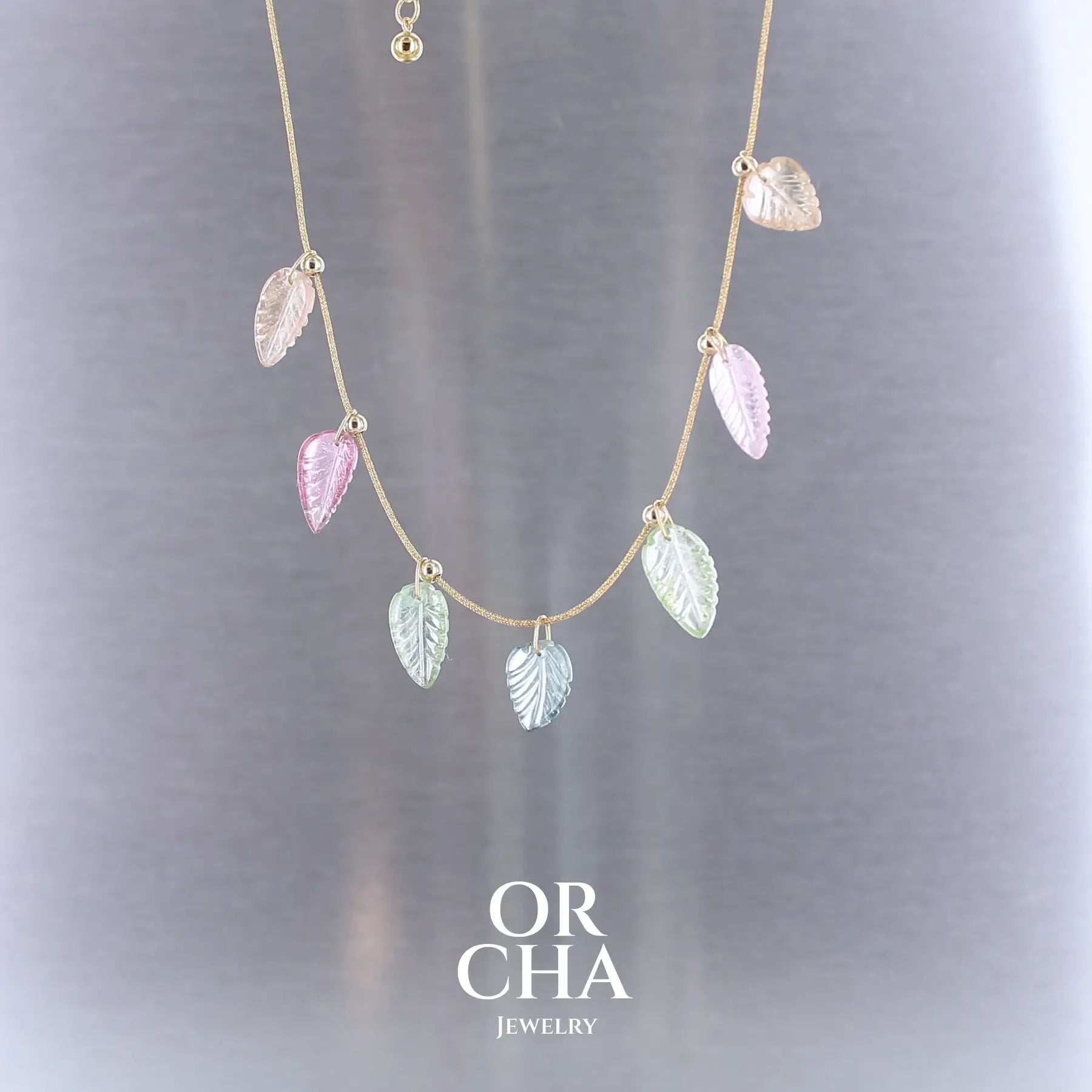 Collier pour femme orné de tourmalines roses, vertes, bleues et pêches, sculptées à la main en 3 dimensions en forme de feuilles et serties en or 18k. Les pendentifs sont montés sur un collier corde doré scintillant, les apprêts utilisé sont en Gold filled ( or laminé ). Longueur ajustable de 40 cm à 45 cm. Bijoux unique, éthique et durable présenté dans un coffret de notre marque, prêt à offrir. Livraison offerte, certificat d'authenticité, service client.