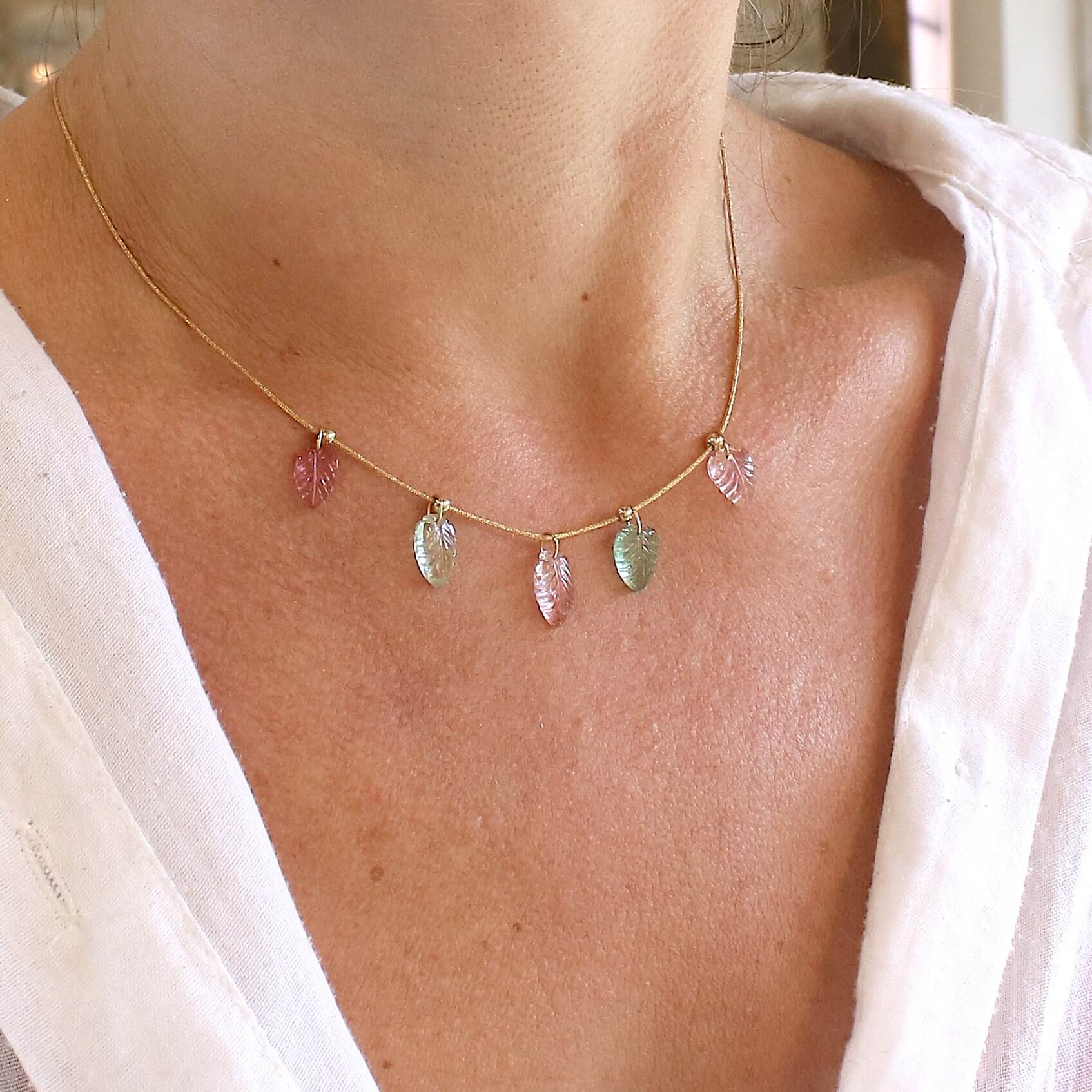 Collier pour femme orné de tourmalines roses et vertes sculptées à la main en 3 dimensions en forme de feuilles serties en or 18k. Les breloques sont montées sur un collier corde doré scintillant, les apprêts utilisé sont en Gold filled ( or laminé ). Longueur ajustable de 40 cm à 45 cm. Bijoux unique, éthique et durable présenté dans un coffret de notre marque, prêt à offrir. Livraison offerte, certificat d'authenticité, service client.