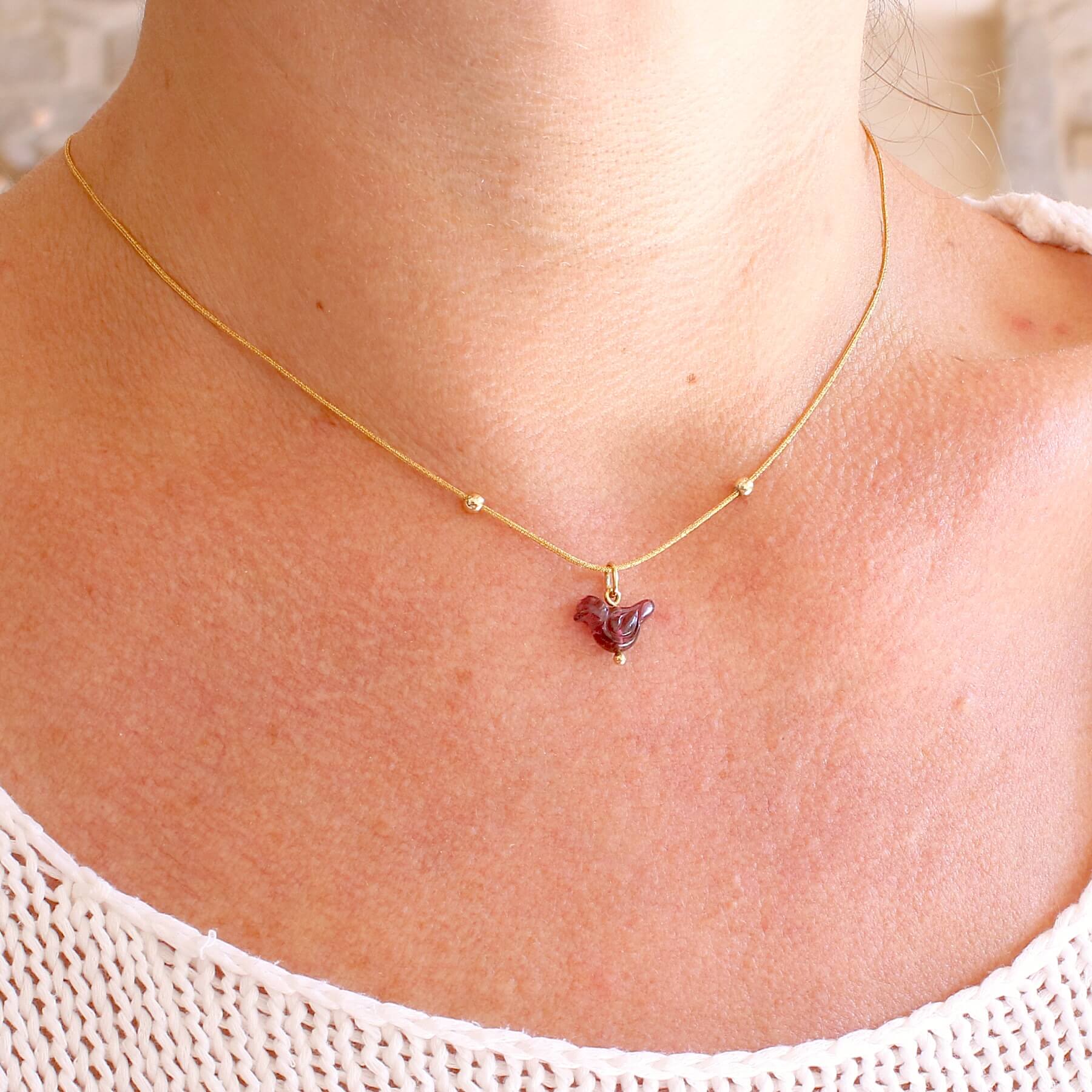 Collier pour femme orné d'une tourmaline rouge violacé sculptée à la main en 3 dimensions en forme d'oiseau sertie en or 18k. Le pendentif est monté sur un collier corde doré scintillant, les apprêts utilisé sont en Gold filled ( or laminé ). Longueur ajustable de 40 cm à 45 cm. Bijoux unique, éthique et durable présenté dans un coffret de notre marque, prêt à offrir. Livraison offerte, certificat d'authenticité, service client.