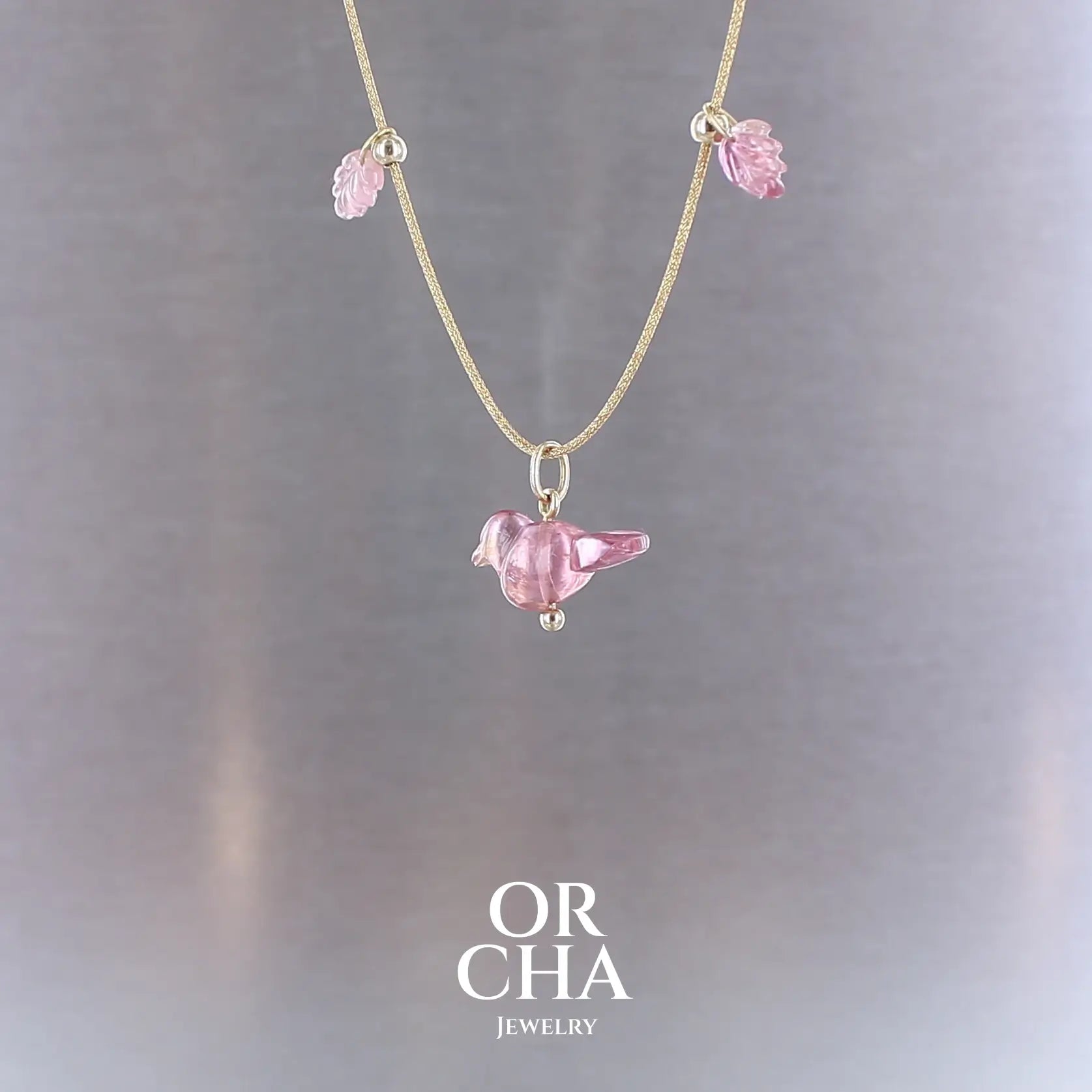 Collier pour femme orné de tourmalines roses sculptées à la main en 3 dimensions en forme d'oiseau et de feuilles, serties en or 18k. Les pendentifs sont montés sur un collier corde doré scintillant, les apprêts utilisé sont en Gold filled ( or laminé ). Longueur ajustable de 40 cm à 45 cm. Bijoux unique, éthique et durable présenté dans un coffret de notre marque, prêt à offrir. Livraison offerte, certificat d'authenticité, service client.