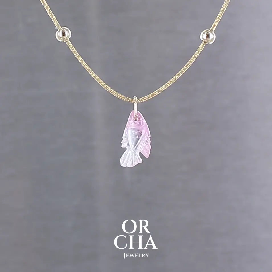 Collier pour femme orné d'une tourmaline rose sculptée à la main en 3 dimensions en forme de poisson sertie en or 18k. Le pendentif est monté sur un collier corde doré scintillant, les apprêts utilisé sont en Gold filled ( or laminé ). Longueur ajustable de 40 cm à 45 cm. Bijoux unique, éthique et durable présenté dans un coffret de notre marque, prêt à offrir. Livraison offerte, certificat d'authenticité, service client.
