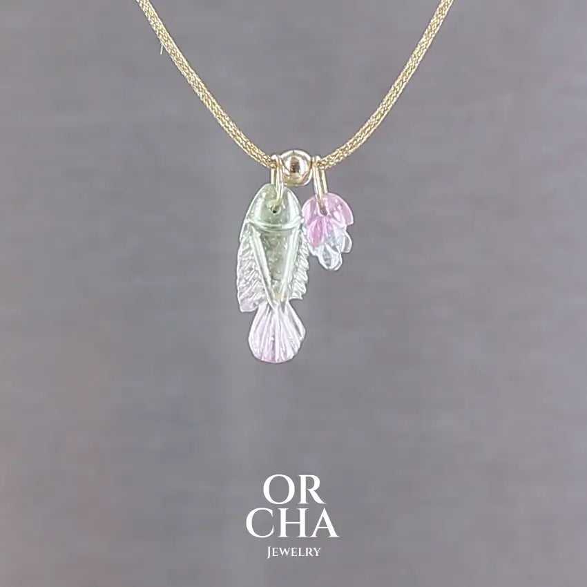 Collier pour femme orné de tourmalines bicolores roses, vertes et bleues, sculptées à la main en 3 dimensions en forme de poisson et de feuille serties en or 18k. Les pendentifs sont montés sur un collier corde doré scintillant, les apprêts utilisé sont en Gold filled ( or laminé ). Longueur ajustable de 40 cm à 45 cm. Bijoux unique, éthique et durable présenté dans un coffret de notre marque, prêt à offrir. Livraison offerte, certificat d'authenticité, service client.
