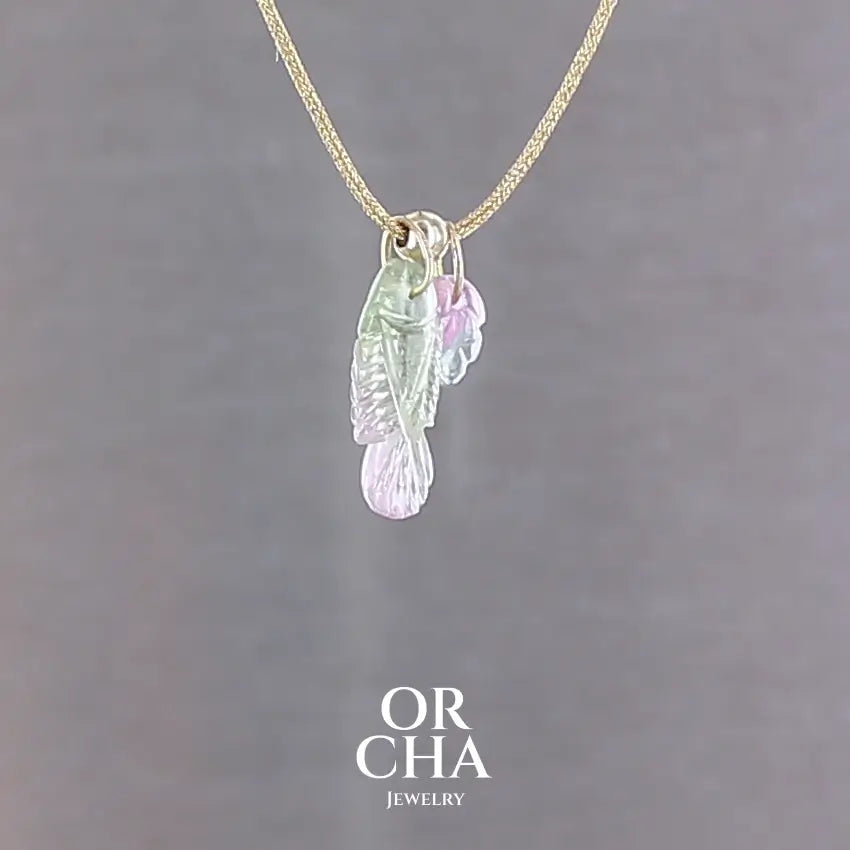 Collier pour femme orné de tourmalines bicolores roses, vertes et bleues, sculptées à la main en 3 dimensions en forme de poisson et de feuille serties en or 18k. Les pendentifs sont montés sur un collier corde doré scintillant, les apprêts utilisé sont en Gold filled ( or laminé ). Longueur ajustable de 40 cm à 45 cm. Bijoux unique, éthique et durable présenté dans un coffret de notre marque, prêt à offrir. Livraison offerte, certificat d'authenticité, service client.