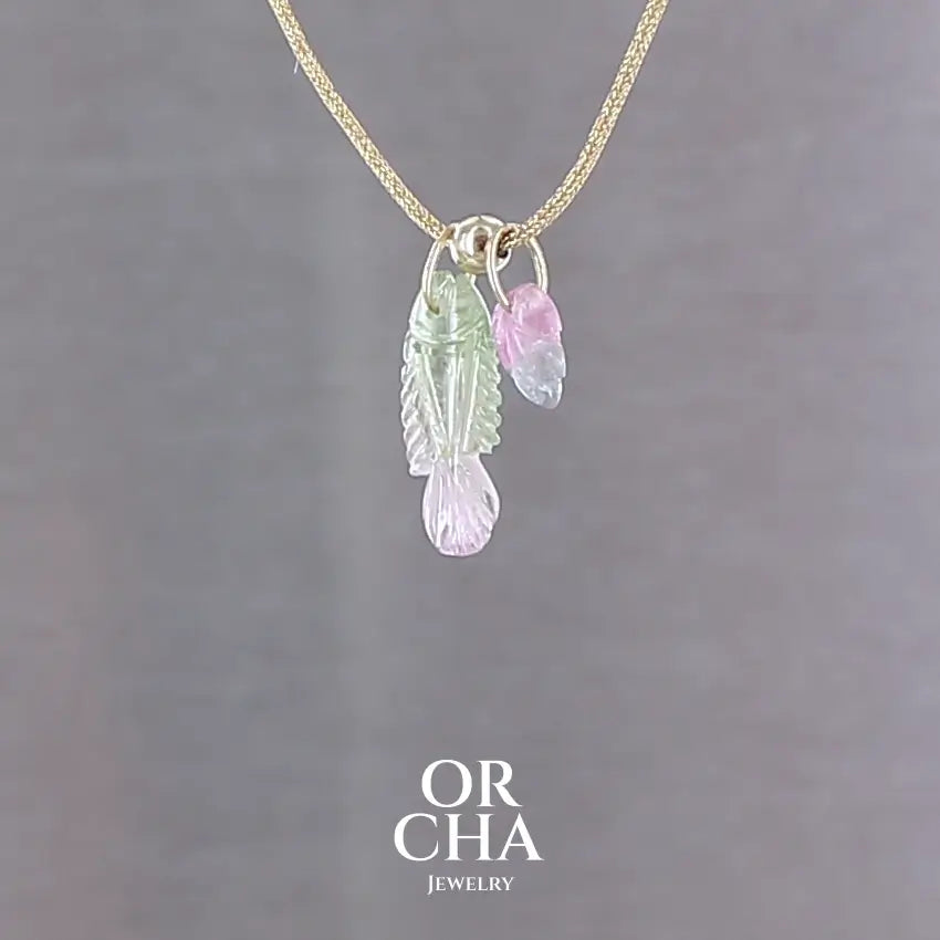 Collier pour femme orné de tourmalines bicolores roses, vertes et bleues, sculptées à la main en 3 dimensions en forme de poisson et de feuille serties en or 18k. Les pendentifs sont montés sur un collier corde doré scintillant, les apprêts utilisé sont en Gold filled ( or laminé ). Longueur ajustable de 40 cm à 45 cm. Bijoux unique, éthique et durable présenté dans un coffret de notre marque, prêt à offrir. Livraison offerte, certificat d'authenticité, service client.