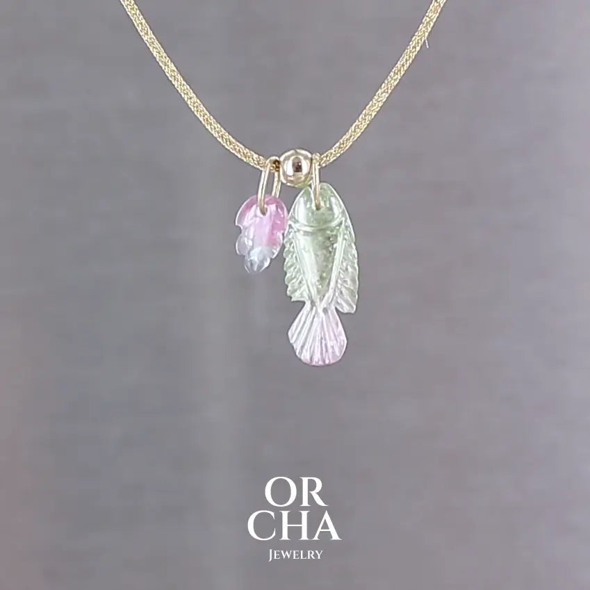 Collier pour femme orné de tourmalines bicolores roses, vertes et bleues, sculptées à la main en 3 dimensions en forme de poisson et de feuille serties en or 18k. Les pendentifs sont montés sur un collier corde doré scintillant, les apprêts utilisé sont en Gold filled ( or laminé ). Longueur ajustable de 40 cm à 45 cm. Bijoux unique, éthique et durable présenté dans un coffret de notre marque, prêt à offrir. Livraison offerte, certificat d'authenticité, service client.