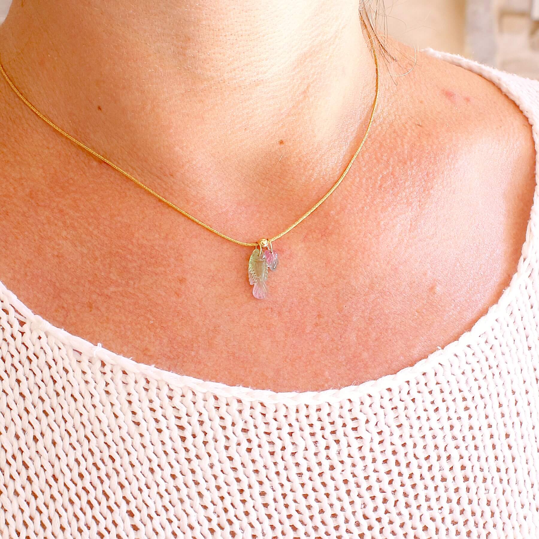 Collier pour femme orné de tourmalines bicolores roses, vertes et bleues, sculptées à la main en 3 dimensions en forme de poisson et de feuille serties en or 18k. Les pendentifs sont montés sur un collier corde doré scintillant, les apprêts utilisé sont en Gold filled ( or laminé ). Longueur ajustable de 40 cm à 45 cm. Bijoux unique, éthique et durable présenté dans un coffret de notre marque, prêt à offrir. Livraison offerte, certificat d'authenticité, service client.