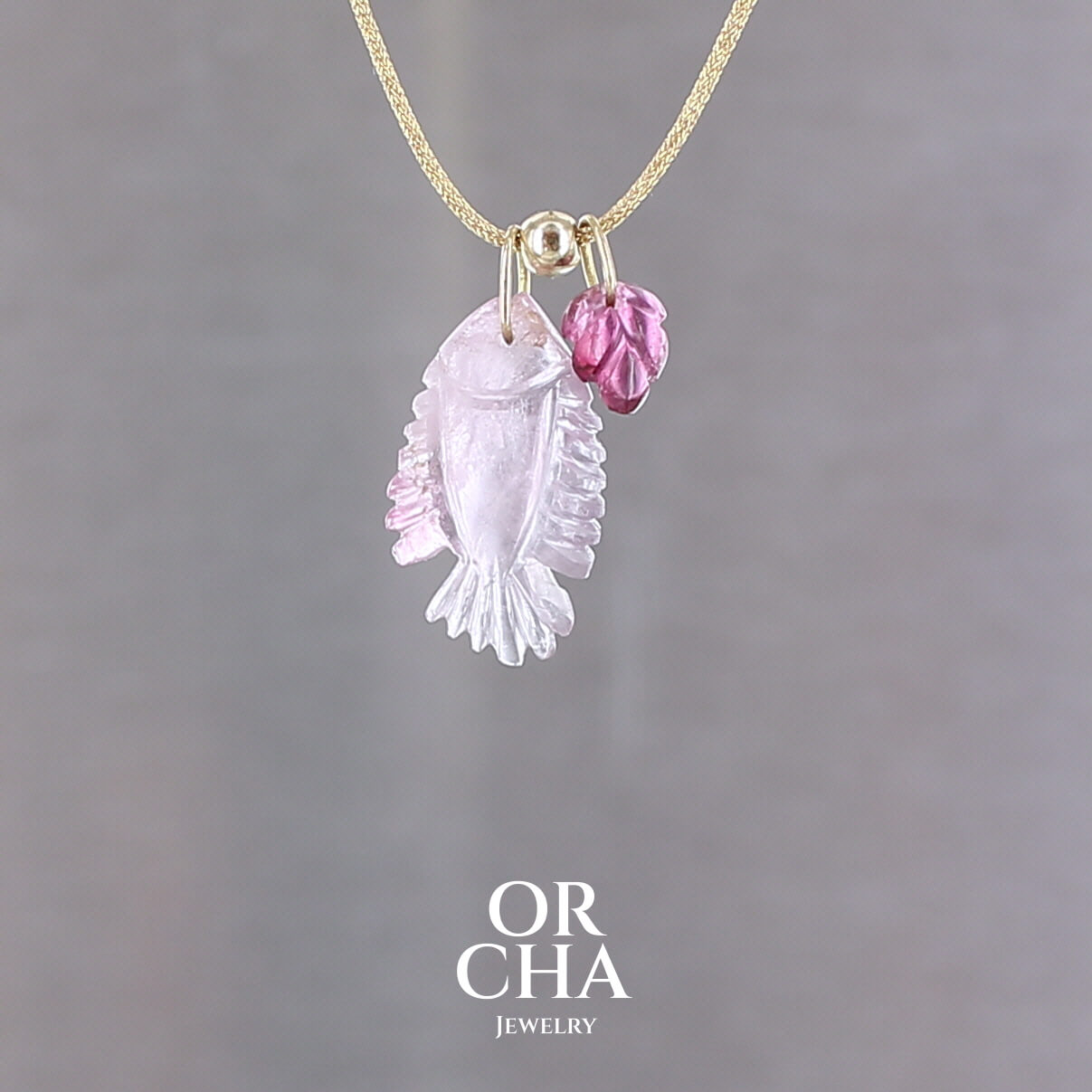 Collier pour femme orné de deux tourmalines roses sculptées à la main en 3 dimensions en forme l'une de poisson  et l'autre de feuille, serties en or 18k. Les pendentifs sont montés sur un collier corde doré scintillant, les apprêts utilisés sont en Gold filled ( or laminé ). Longueur ajustable de 40 cm à 45 cm. Bijoux unique, éthique et durable présenté dans un coffret de notre marque, prêt à offrir. Livraison offerte, certificat d'authenticité, service client.
