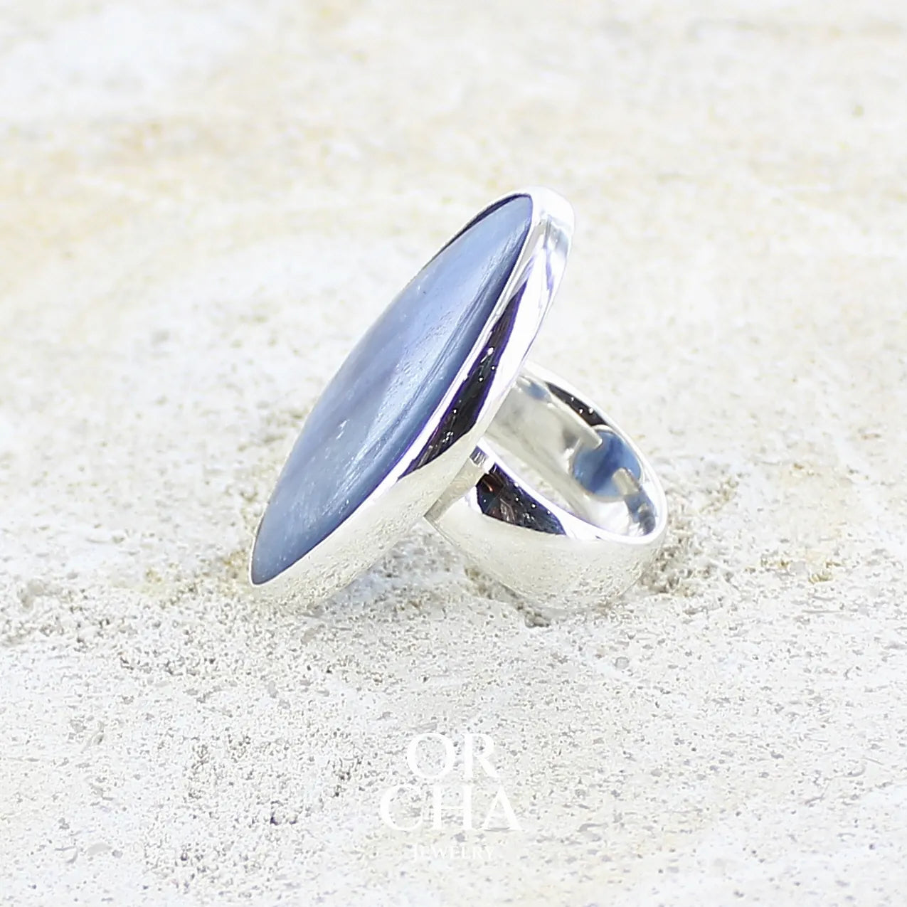 détail sertissage d'une bague pour femme en argent massif sertie d'un cabochon de cyanite de couleur bleu jean nacré. Pierre translucide à inclusions. Bijou unique réalisée en taille 54 par Orcha Jewelry