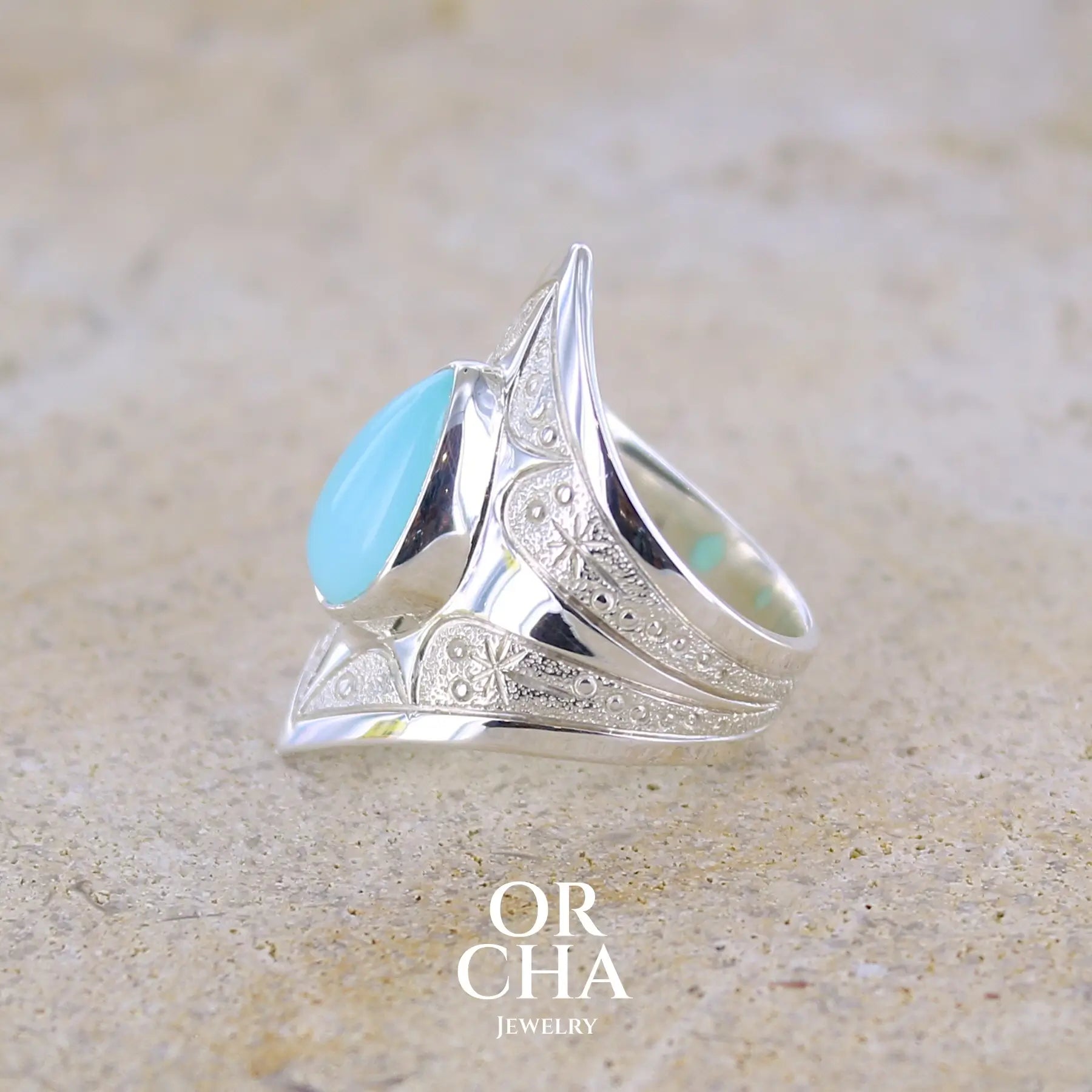 détail texture d'une bague pour femme en argent massif sculptées d'étoiles et autres corps célestes sertie d'une Opale bleue du Pérou. Pierre cabochon en forme de goutte, pierre naturelle de couleur bleu ciel ciel, bleu turquoise. Pierre naturelle de qualité opaque. Taille 51. Bijoux unique, éthique et durable présenté dans un coffret de notre marque, prêt à offrir. Livraison offerte, certificat d'authenticité, service client.