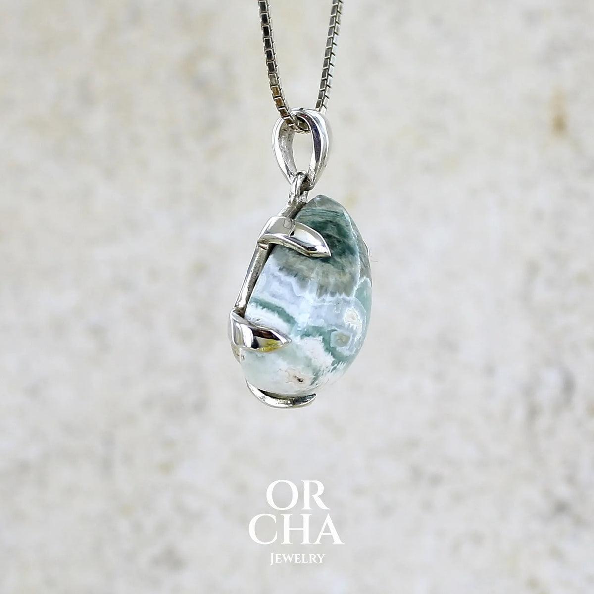 détail du sertissage d'un pendentif pour femme en argent massif sertie d'un cabochon de jaspe océan de couleur nuancée de kaki et crème. Pierre opaque taillée en forme de goutte. Bijou unique par Orchajewelry
