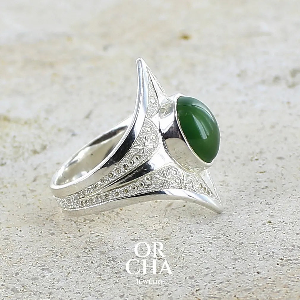 Détails gravures d'une bague pour femme en argent massif sculptées d'étoiles et autres corps célestes sertie d'un cabochon ovale de préhnite de couleur verte pastel lumineuse. Pierre naturelle de qualité transparente présentant des inclusions. Bijoux unique réalisé en taille 54,5 par Orchajewelry.