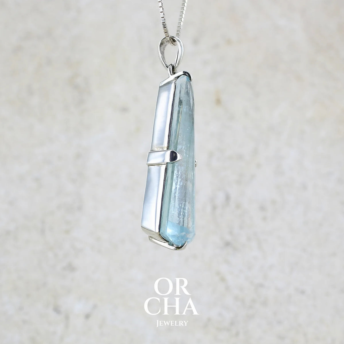détail d'un pendentif en argent massif sertie d'une aigue marine taillée de 32 carats de couleur bleu clair profond et lumineux, pierre transparente avec inclusions. Pierre naturelle facettée de forme triangulaire allongé. Bijoux unique réalisée par Orchajewelry