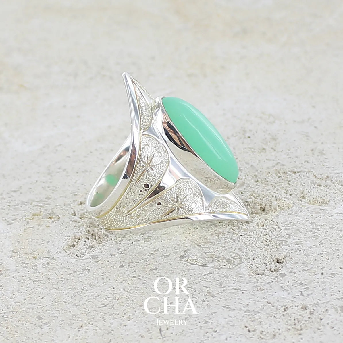 détail de l'anneau d'une bague marquise pour femme en argent massif sculptées d'étoiles et autres corps célestes sertie d'un cabochon de chrysoprase de couleur verte pastel. Pierre naturelle de qualité translucide taillée en ovale longiligne. Bague unique réalisée en taille 57 par Orcha jewelry