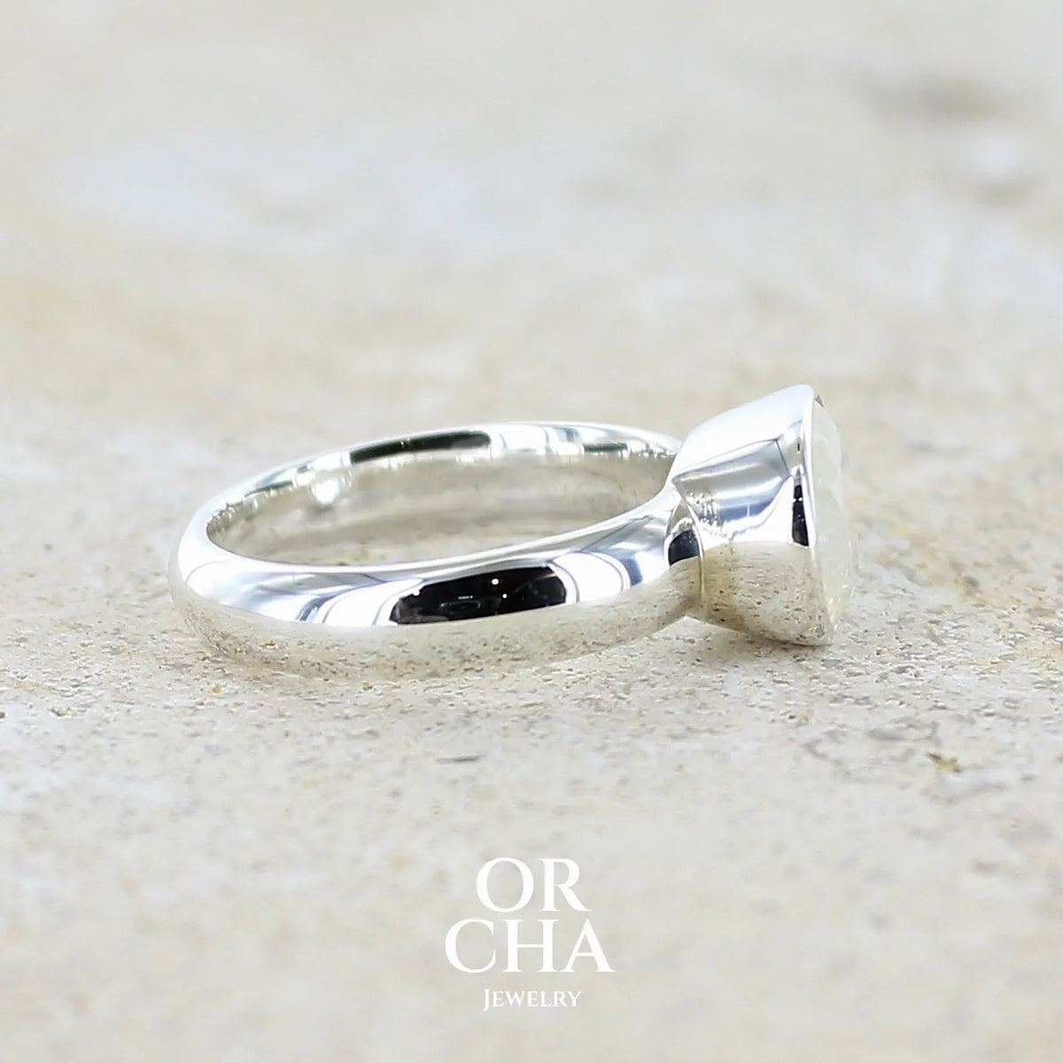 Détail d'une bague cocktail pour femme en argent massif 925 sertie d'une pierre de lune arc en ciel de Madagascar taillée de 2,5 carats incolore aux reflets bleutés et arc en ciel. Pierre transparente avec inclusions. Bijoux unique réalisée en taille 56 par Orchajewelry