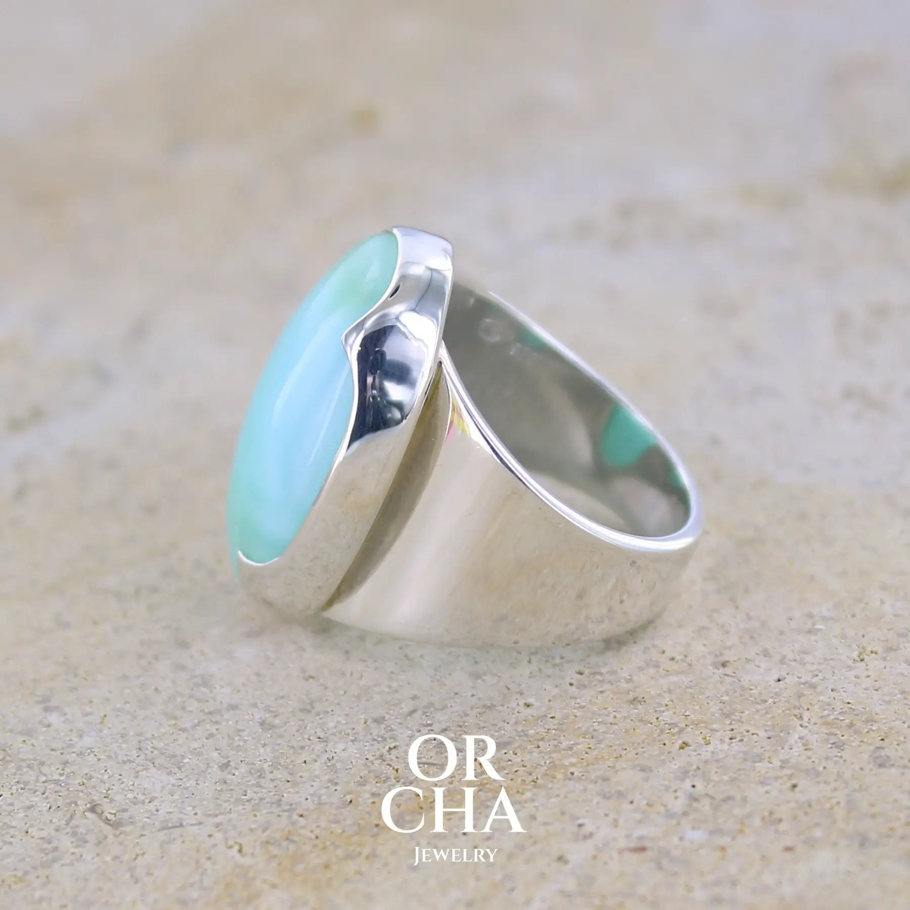 Détail sertissage  d'une grande Bague pour femme en argent massif, sertie d'un cabochon d'opale bleue du Pérou. Pierre taillée de forme ovale. Pierre opaque. Taille 58,5. Bijoux unique, éthique et durable présenté dans un coffret de notre marque, prêt à offrir. Livraison offerte, certificat d'authenticité, service client.
