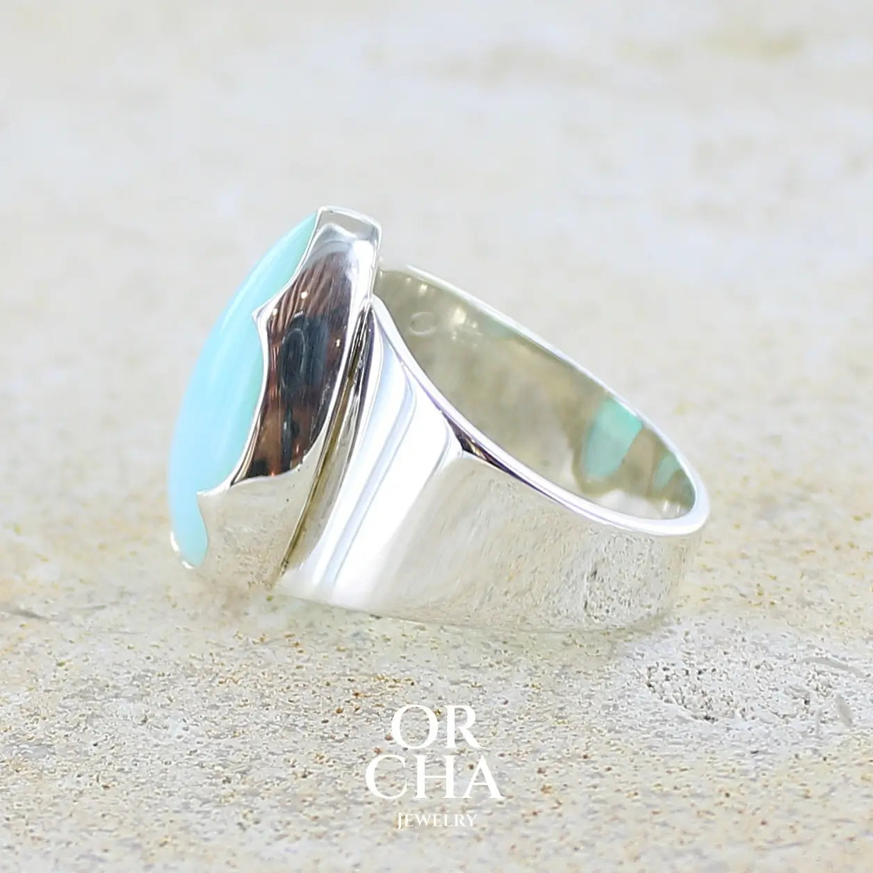 Détail texture d'une bague pour femme en argent massif, sertie d'un cabochon d'opale bleue du Pérou de couleur bleu ciel. Pierre taillée en forme de goutte de qualité opaque. Bijou unique réalisé en taille 58. 