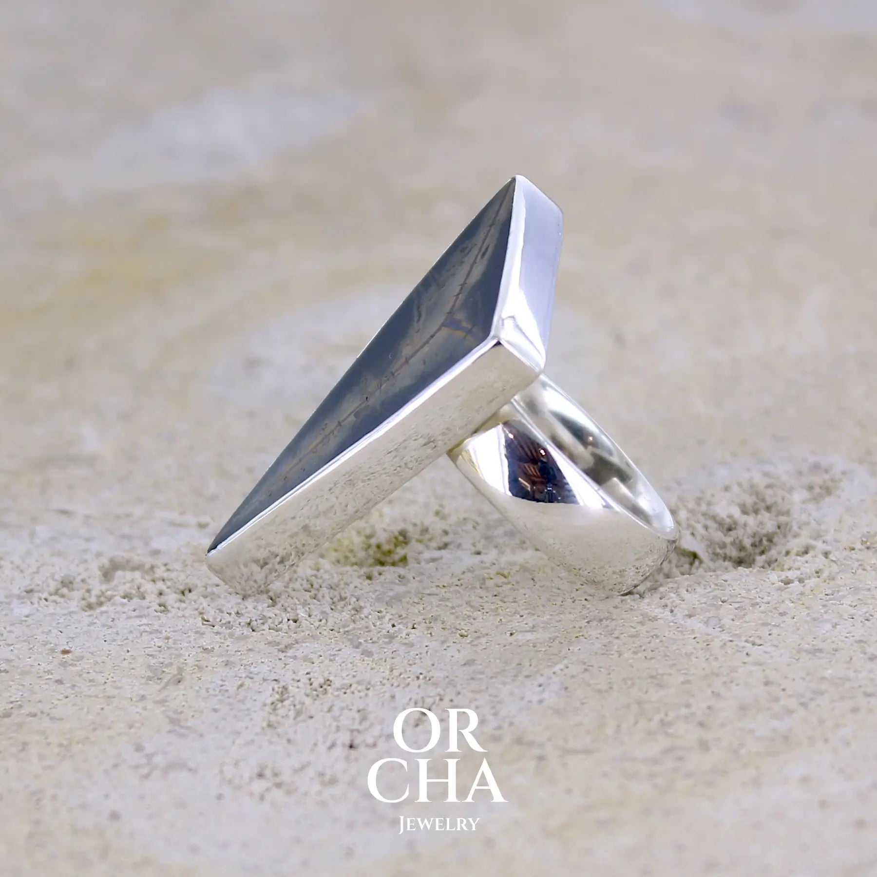 détail du sertissage d'une grande bague contemporaine pour femme en argent massif sertie d'une tranche de septaria Pierre unique et rare sous cette forme triangulaire. Pierre de qualité opaque naturelle de couleur brun foncé à brun clair. Bague réalisée en taille 54.  Bijoux unique, éthique et durable présenté dans un coffret de notre marque, prêt à offrir. Livraison offerte, certificat d'authenticité, service client.
