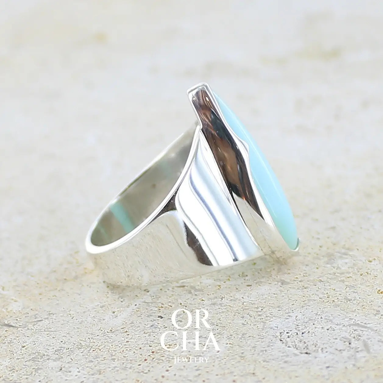 détail du sertissage d'une bague pour femme en argent massif, sertie d'un cabochon d'opale bleue du Pérou de couleur bleu ciel. Pierre taillée en forme de goutte longiligne, de qualité opaque. Bijou unique réalisé en taille 53,5. 