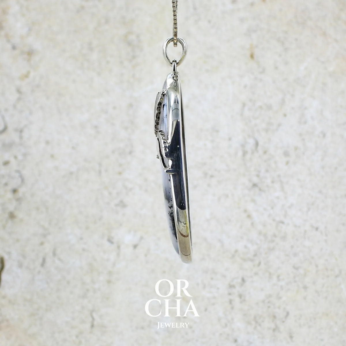 Détail du sertissage pendentif en argent massif sertie d'un grand cabochon de forme ovale d'agate dendritique de couleur blanc pur et noir. Pierre opaque à translucide à inclusions paysages de dendrites de manganèse noires contrastées. Bijou unique illustré d'un cheval ailé réalisé par Orchajewelry