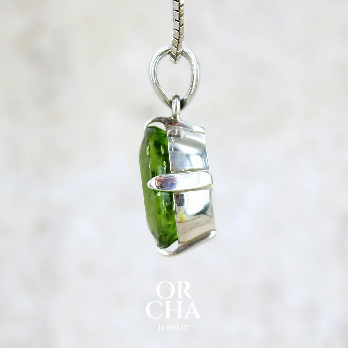 Détail du sertissage d'un pendentif pour femme en argent massif serti d'un Péridot de couleur vert olive doré profond et intense . Pierre taillée transparente présentant des inclusions, de forme ovale. Bijoux unique par Orchajewelry