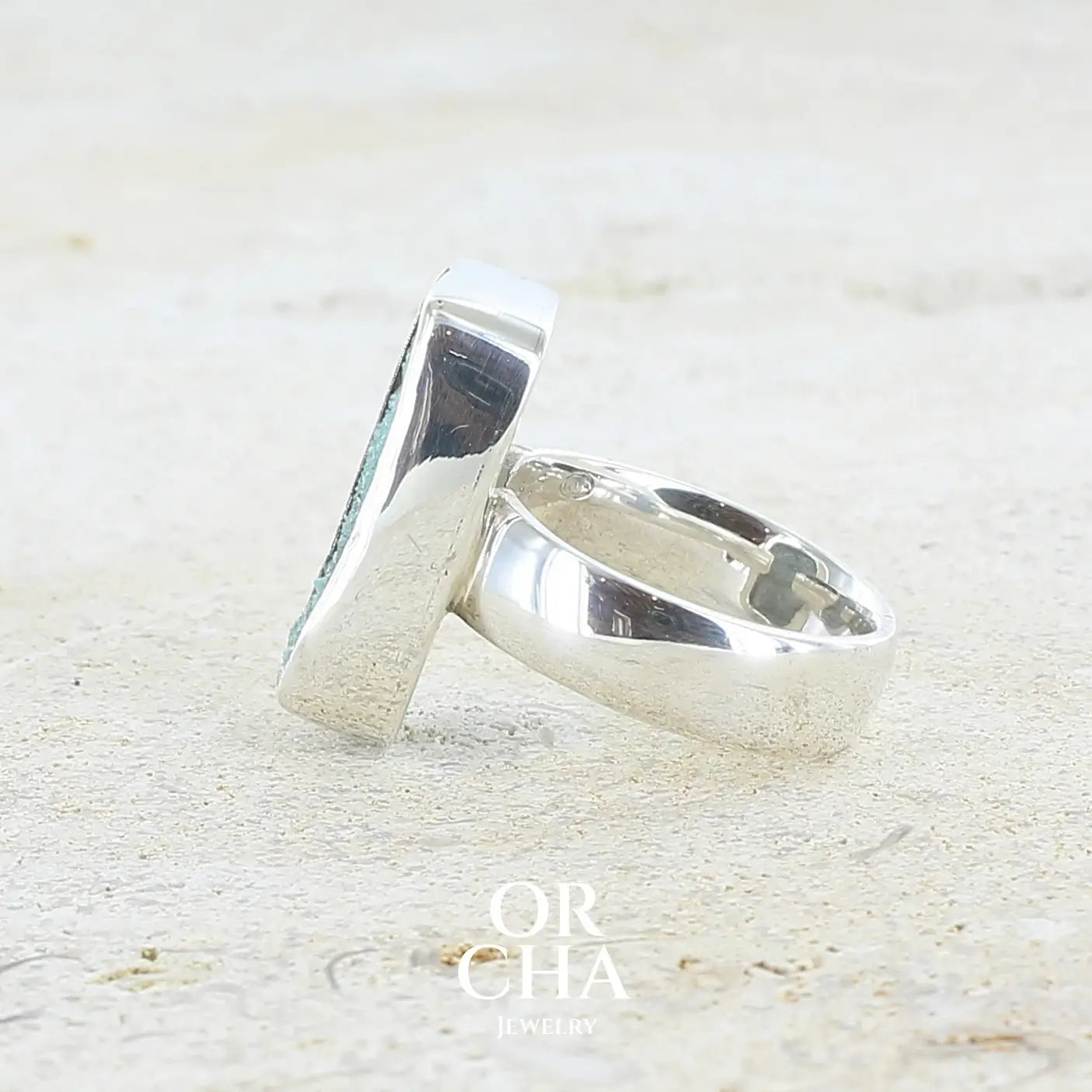 détail texture d'une bague pour femme en argent massif sertie d'un magnifique gemsilica druzy: chrysocale solidifiée recouverte de fins cristaux de quartz scintillant. Pierre de qualité opaque taillée en tranche de forme rectangulaire. Pierre naturelle originaire de République dominicaine du Congo de couleur turquoise, verte et noire. Taille 56. Bijoux unique, éthique et durable présenté dans un coffret de notre marque, prêt à offrir. Livraison offerte, certificat d'authenticité, service client.