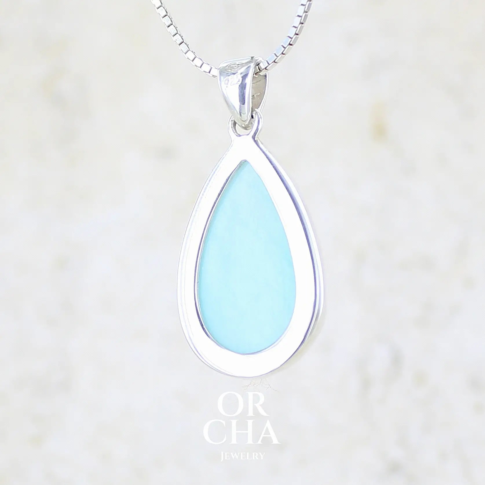vue de dos d'un pendentif en argent massif, sertie d'un cabochon d'opale bleue du Pérou de couleur bleu ciel clair. Pierre en forme de goutte. Pierre opaque et translucide. Bijoux unique, éthique et durable présenté dans un coffret de notre marque, prêt à offrir. Livraison offerte, certificat d'authenticité, service client.