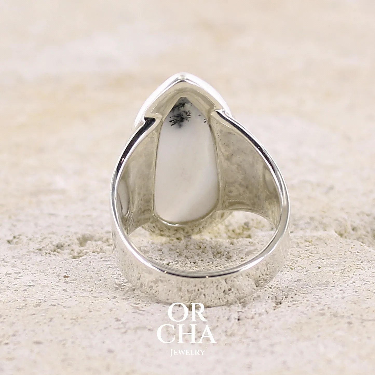 Vue de dos d'une bague pour femme en argent massif sertie d'un cabochon d'agate dendritique de couleur blanche et noire. Pierre translucide à inclusions paysages de manganèse contrastées. Bijou unique réalisée en taille 58 par Orcha Jewelry
