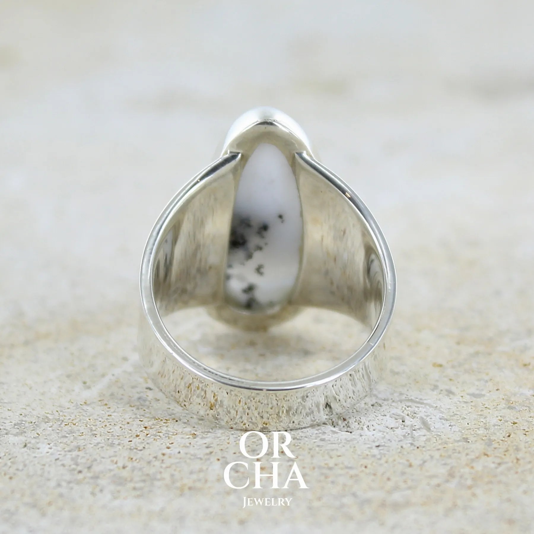 Vue de dos d'une bague pour femme en argent massif sertie d'un cabochon ovale d'agate dendritique de couleur blanc pur et noir. Pierre opaque translucide à inclusions paysages de dendrites de manganèse noires contrastées. Bijou unique réalisée en taille 60 par Orchajewelry