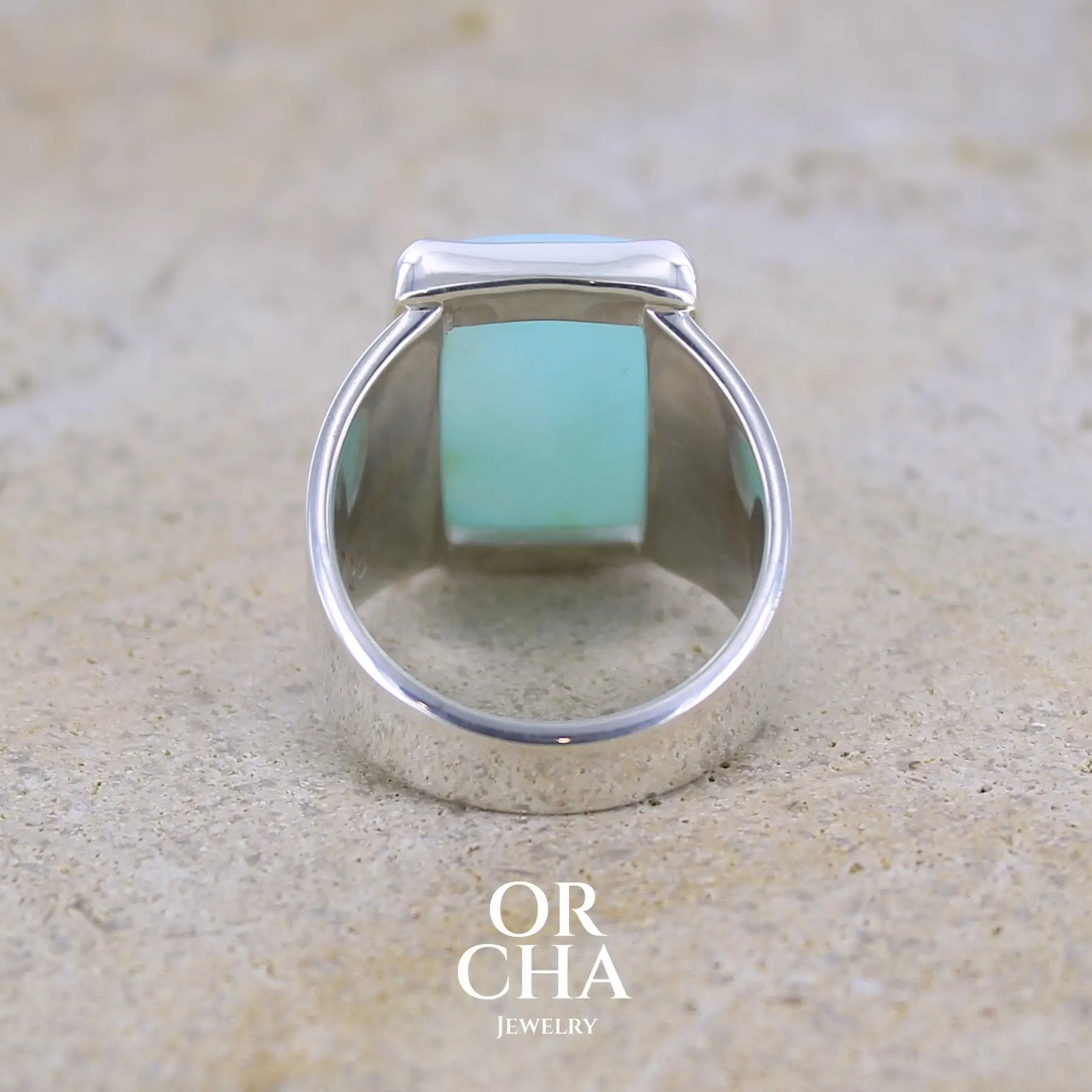 vue de dos d'une bague pour femme en argent massif sculptées d'étoiles et autres corps célestes sertie d'une Opale bleue du Pérou. Pierre cabochon en forme de rectangle, pierre naturelle de couleur bleu ciel ciel, bleu turquoise. Pierre naturelle de qualité opaque. Taille 58. Bijoux unique, éthique et durable présenté dans un coffret de notre marque, prêt à offrir. Livraison offerte, certificat d'authenticité, service client.