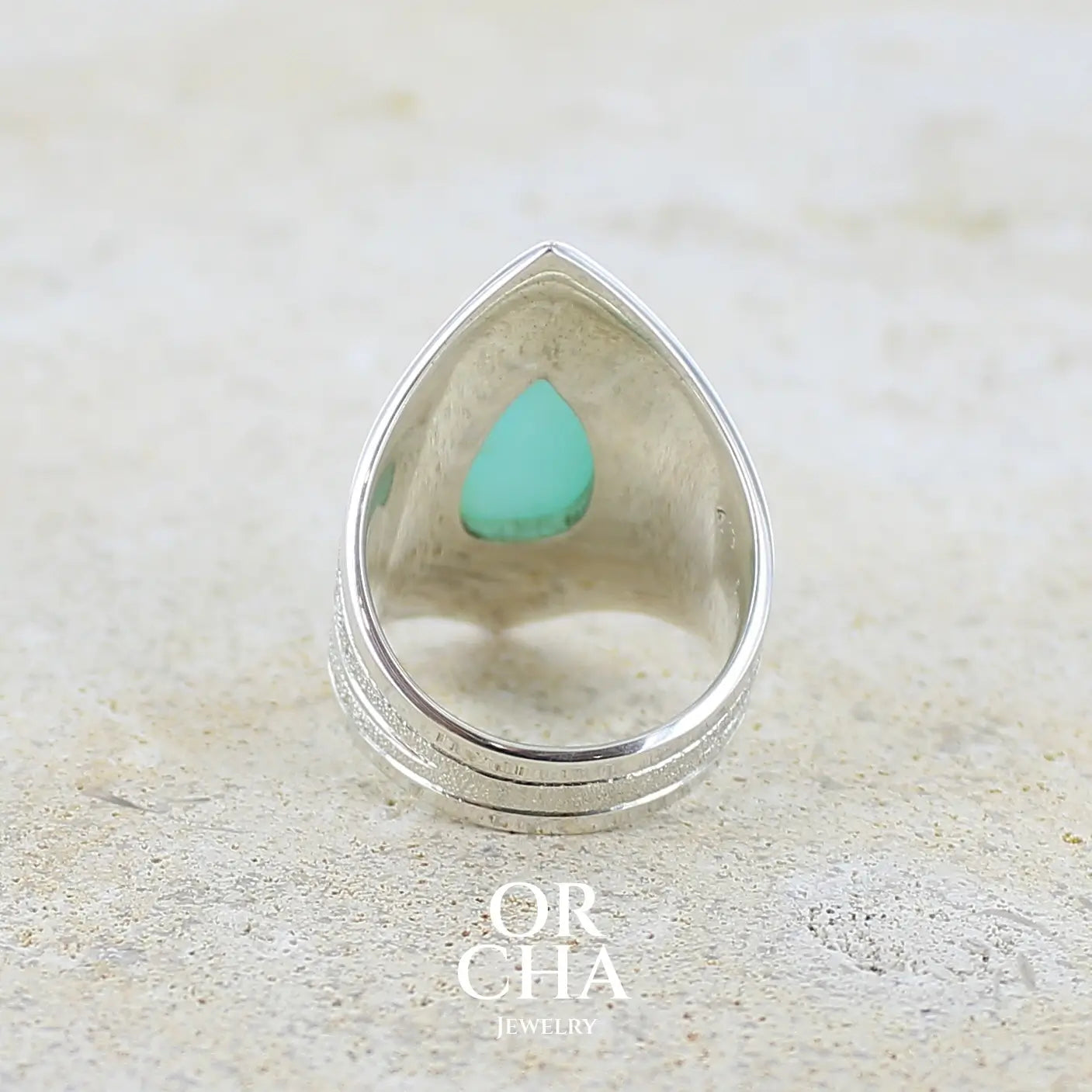 Vue de dos d'une grande Bague pour femme en argent massif, sertie d'un cabochon d'opale bleue du Pérou de couleur bleu ciel turquoise. Pierre taillée en forme de goutte. de qualité opaque. bijou unique réalisé en taille 52.  