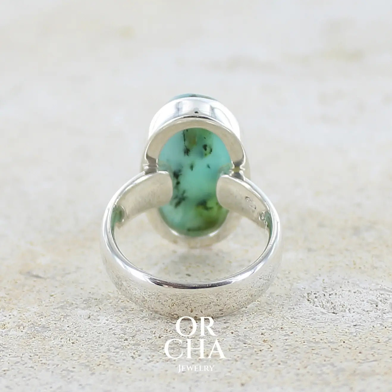 vue de dos d'une bague en argent massif, sertie d'un cabochon ovale d'opale bleue du Pérou de couleur bleu foncé à inclusions de dendrites paysages noires et de roche mère jaune. Pierre naturelle opaque et translucide. Bijoux unique réalisé en taille 52 par Orcha jewelry