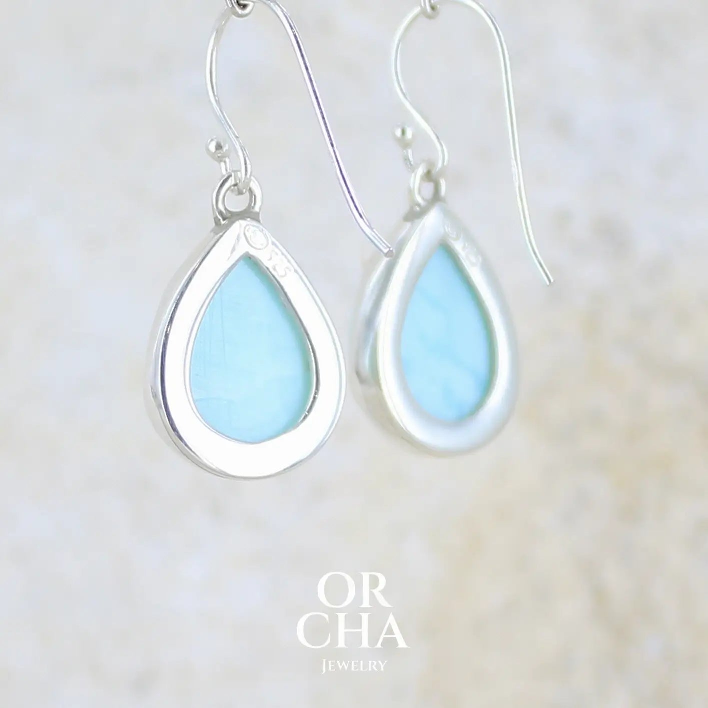 vue de dos de  boucles d'oreilles pendantes en argent massif serties d'opale bleue du Pérou. Pierres cabochon taillée en goutte de qualité opaque. Pierre naturelle de couleur bleu ciel. Bijoux unique, éthique et durable présenté dans un coffret de notre marque, prêt à offrir. Livraison offerte, certificat d'authenticité, service client.