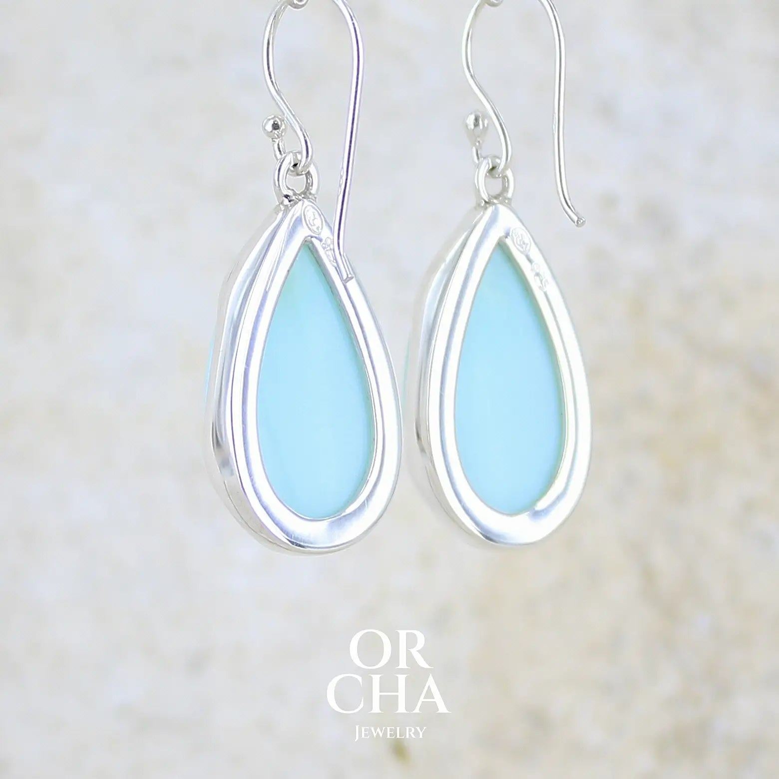 vue de dos boucles d'oreilles pendantes en argent massif serties d'opale bleue du Pérou. Pierres cabochon taillée en goutte de qualité opaque. Pierre naturelle de couleur bleu ciel. Bijoux unique, éthique et durable présenté dans un coffret de notre marque, prêt à offrir. Livraison offerte, certificat d'authenticité, service client.