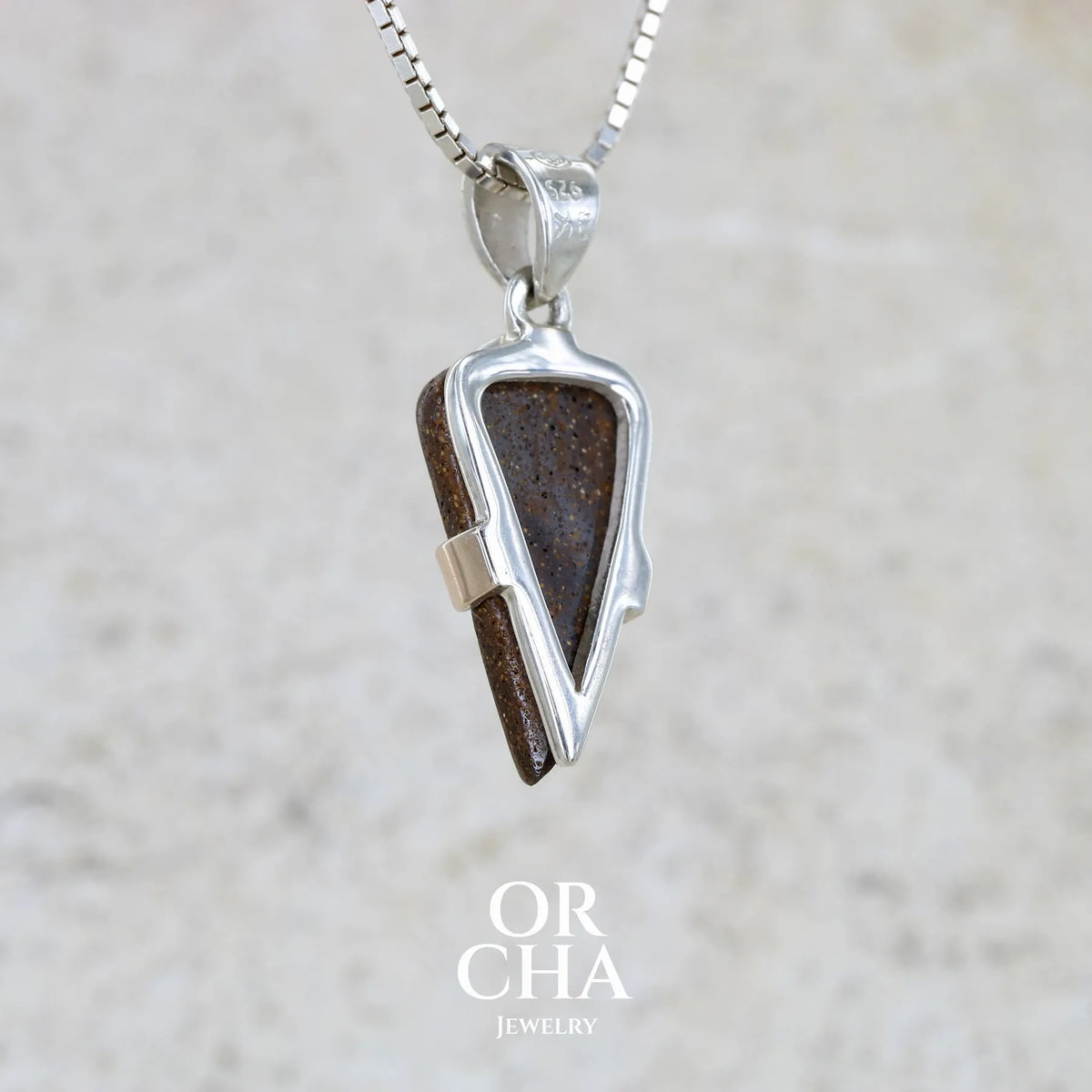 Vue de dos d'un pendentif pour homme en or 9k et argent massif 925 serti d'une opale boulder aux feux multicolores bleus et verts. Tranche d'opale massive naturelle taillée en forme d'aile. Pierre de qualité opaque originaire d'Australie. Bijoux unique par Orcha Jewelry.