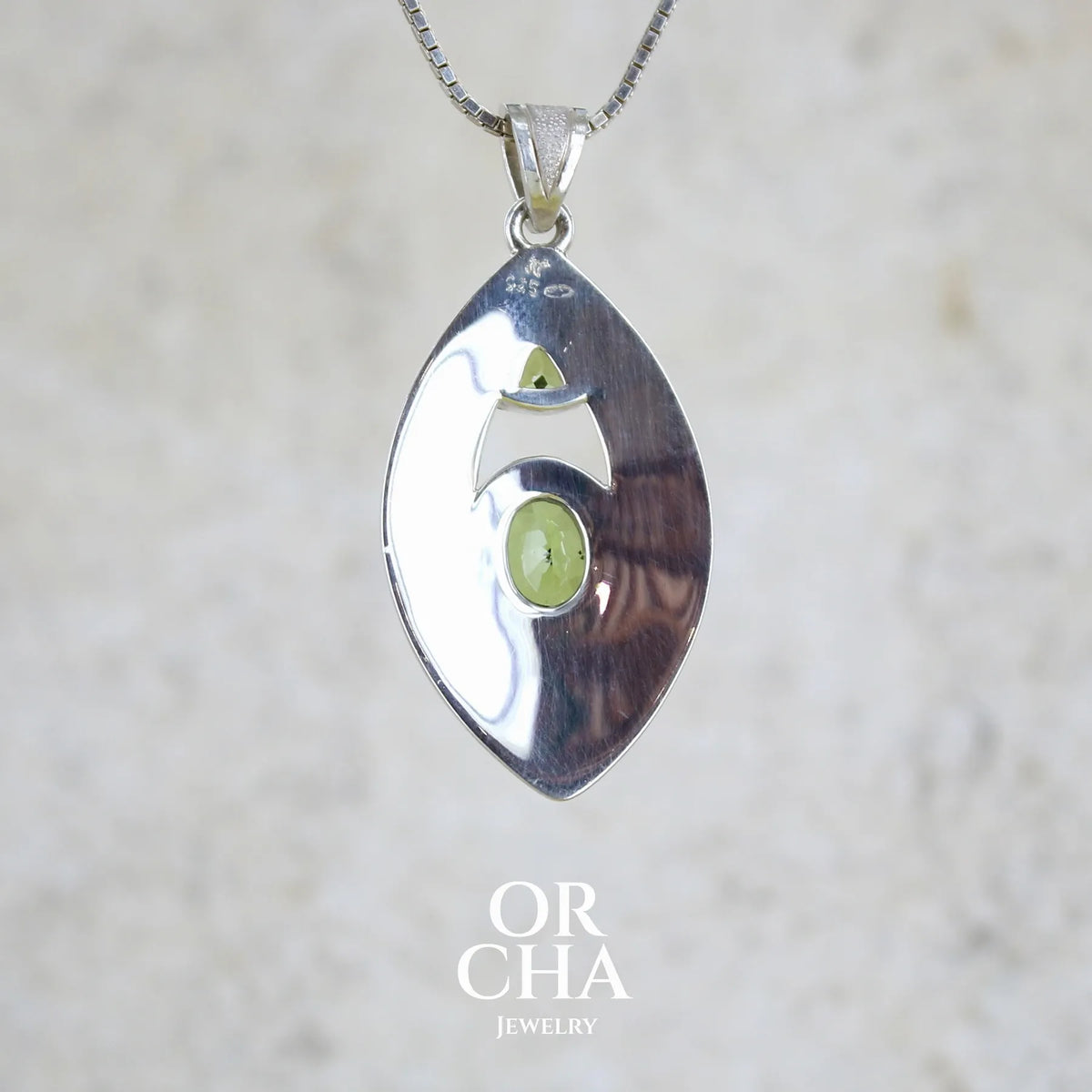 vue de dos d'un pendentif pour femme en argent massif serti d'un péridot de couleur vert olive doré intense. Pierre taillée, de forme ovale, transparente propre à l'oeil. Bijou unique réalisé par Orchajewelry
